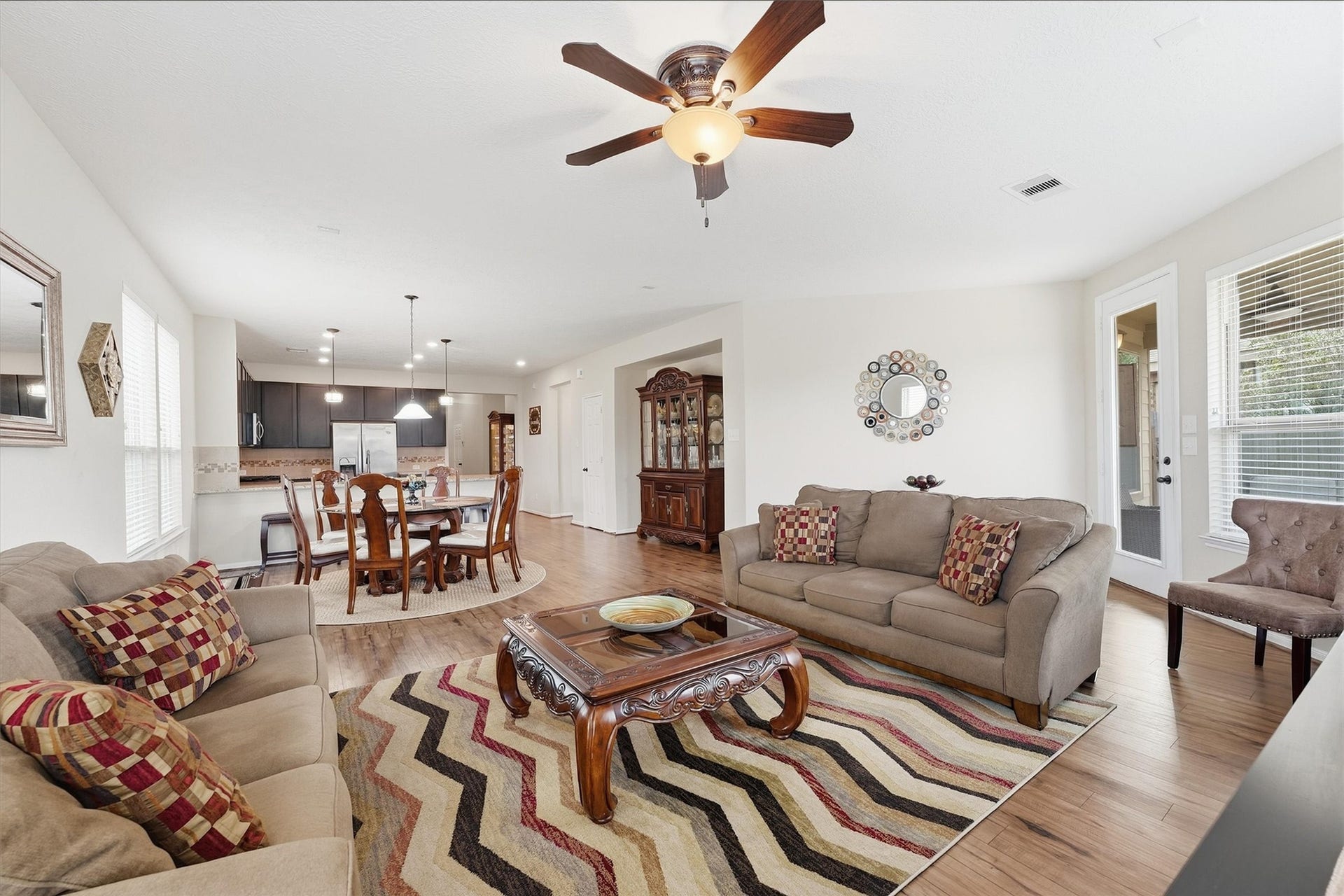 25522 Brentmoor Drive, Porter, TX 77365 Sweeping reverse view across the airy living room directly into the dining and kitchen areas, highlighting the continuous wood-look flooring and soaring open feel.