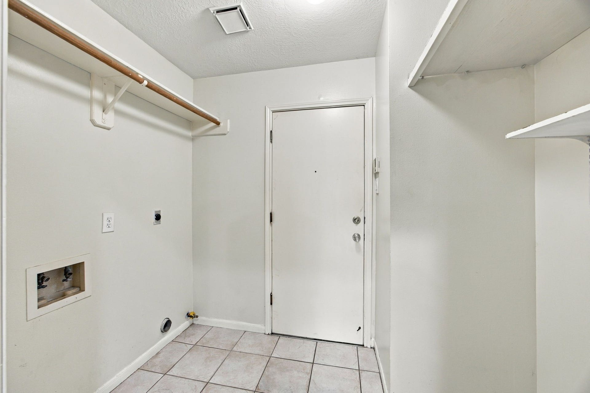 12902 Sandri Lane, Houston, TX 77077 A dedicated laundry room includes washer and dryer connections, open shelving, and a hanging rod for added convenience.