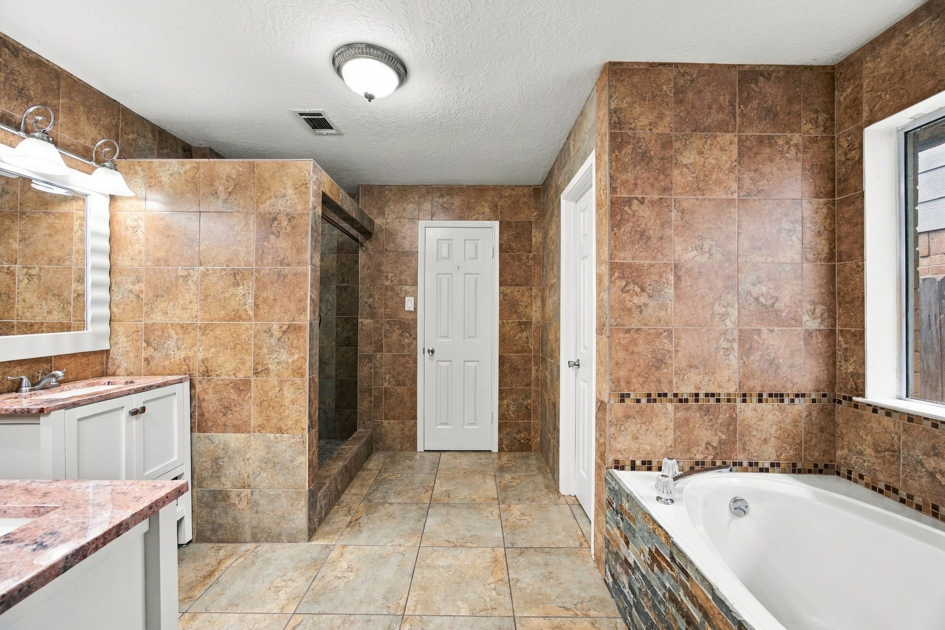 12902 Sandri Lane, Houston, TX 77077 Warm tile surrounds a primary bath with a soaking tub and a separate walk-in shower.