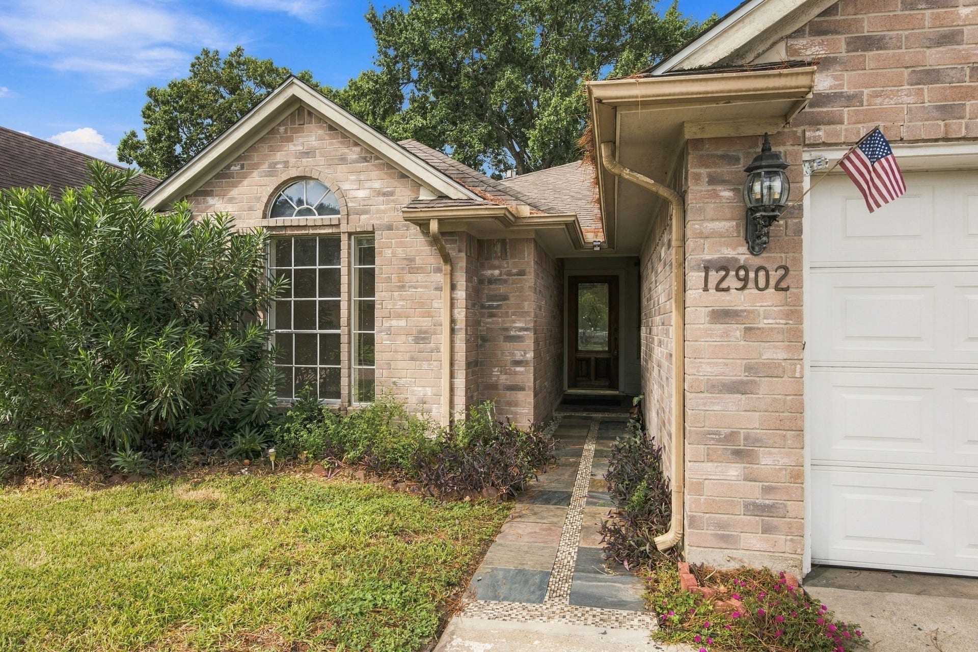 12902 Sandri Lane, Houston, TX 77077 A tiled walkway leads to the recessed entry, with an arched front window adding architectural charm.