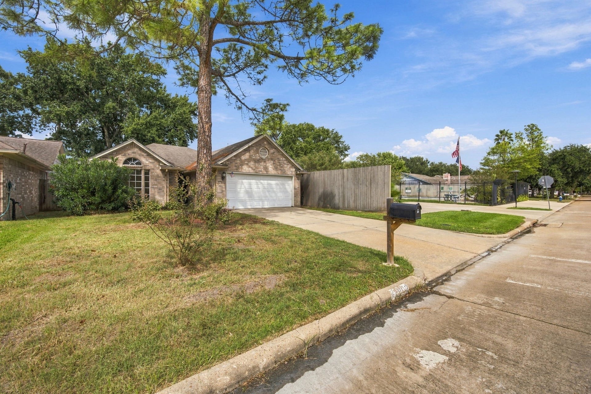 12902 Sandri Lane, Houston, TX 77077 A wider view highlights the front lawn and the homes setting along the residential street.