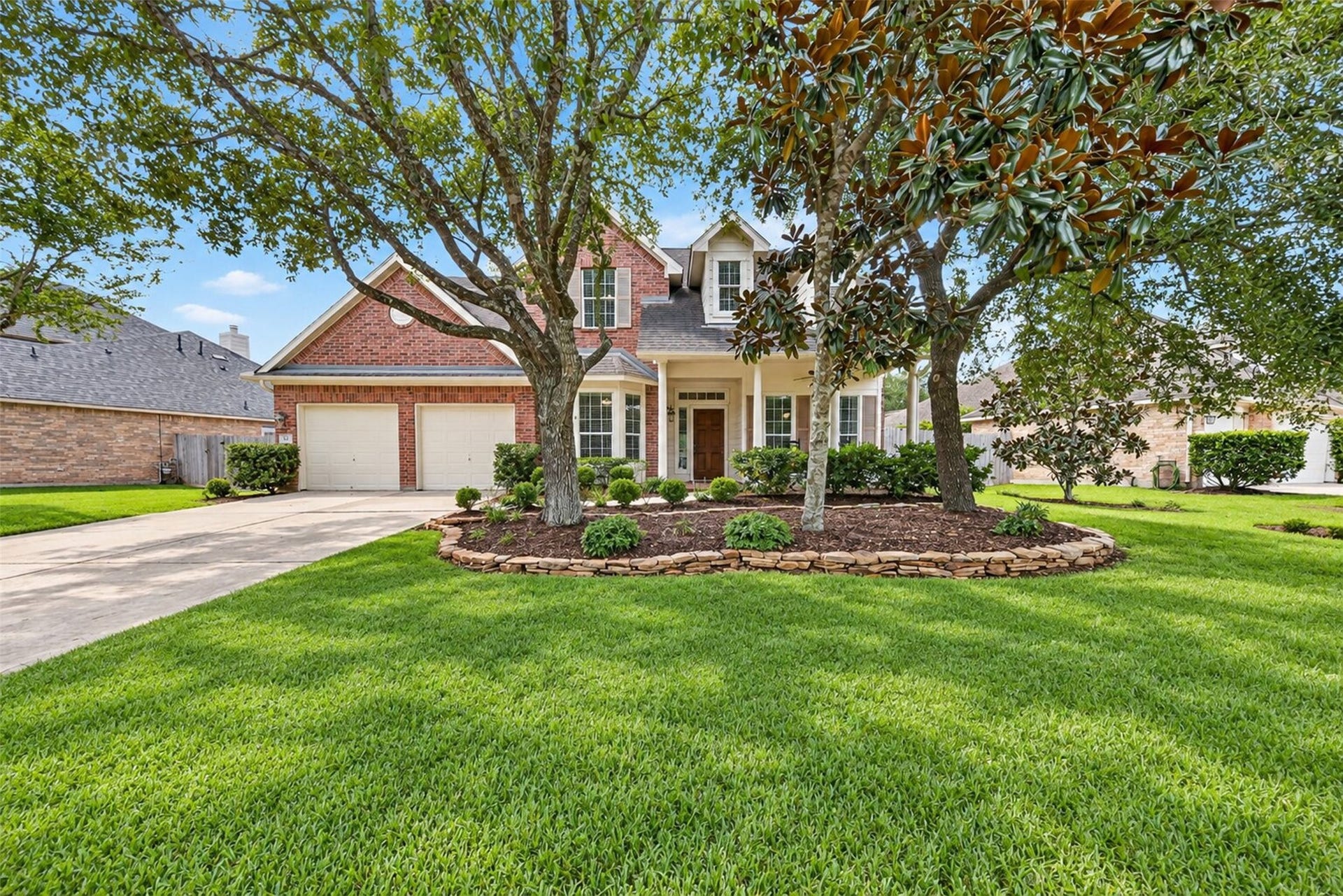 127 N Hawthorne Hollow Circle, The Woodlands, TX 77384 Classic brick exterior framed by mature trees, manicured landscaping, and a welcoming covered front porch.