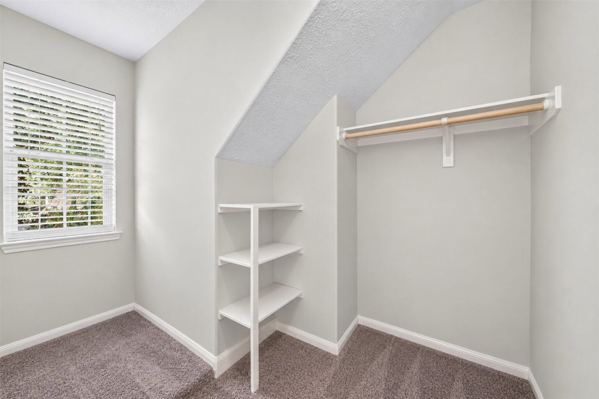 127 N Hawthorne Hollow Circle, The Woodlands, TX 77384 Charming walk-in closet featuring built-in shelving, generous hanging space, and a sweet window nook filled with natural light.