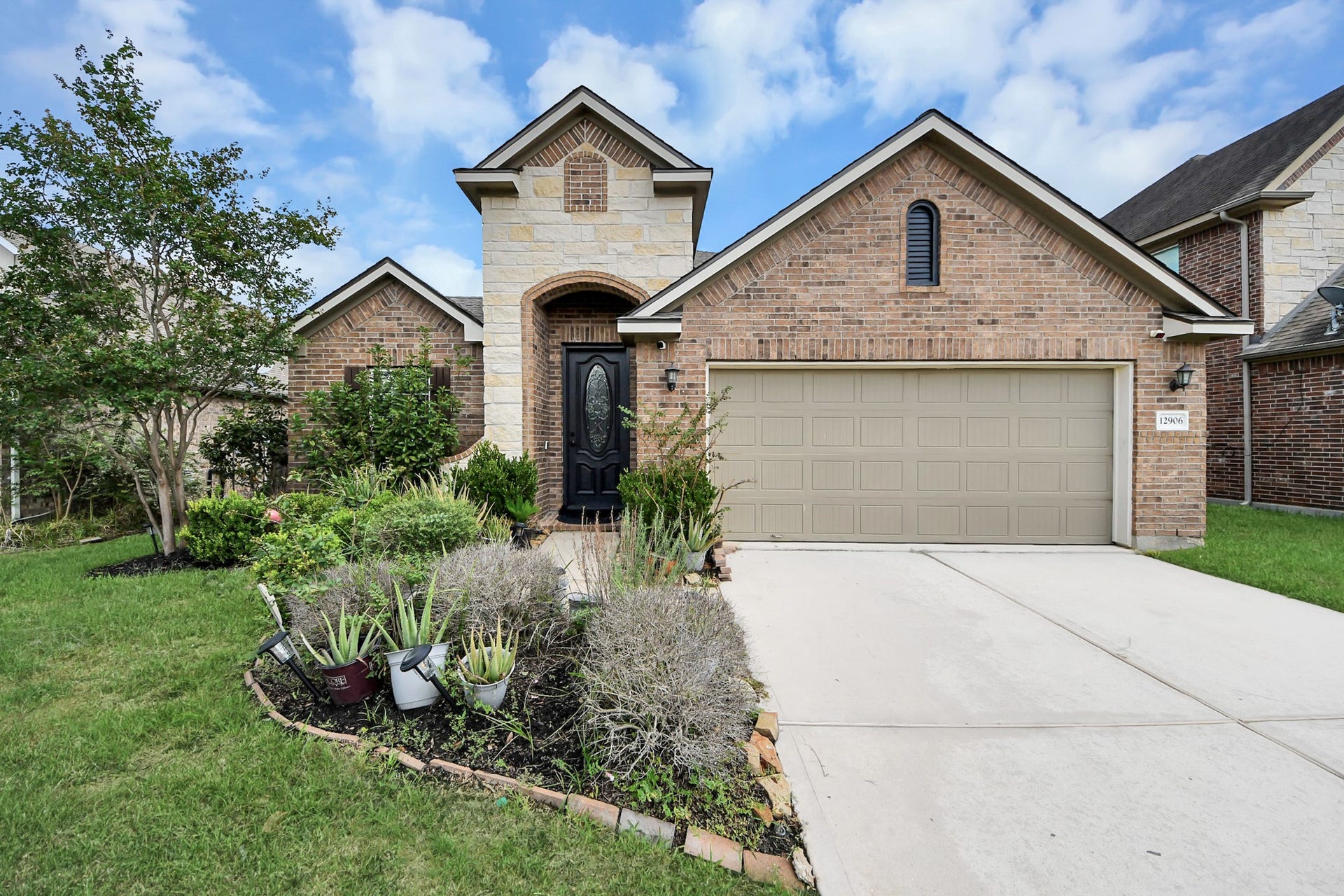 12906 Millstream Bend Lane, Tomball, TX 77377 Charming brick home with an inviting arched entryway, well-maintained landscaping, and a spacious two-car garage.