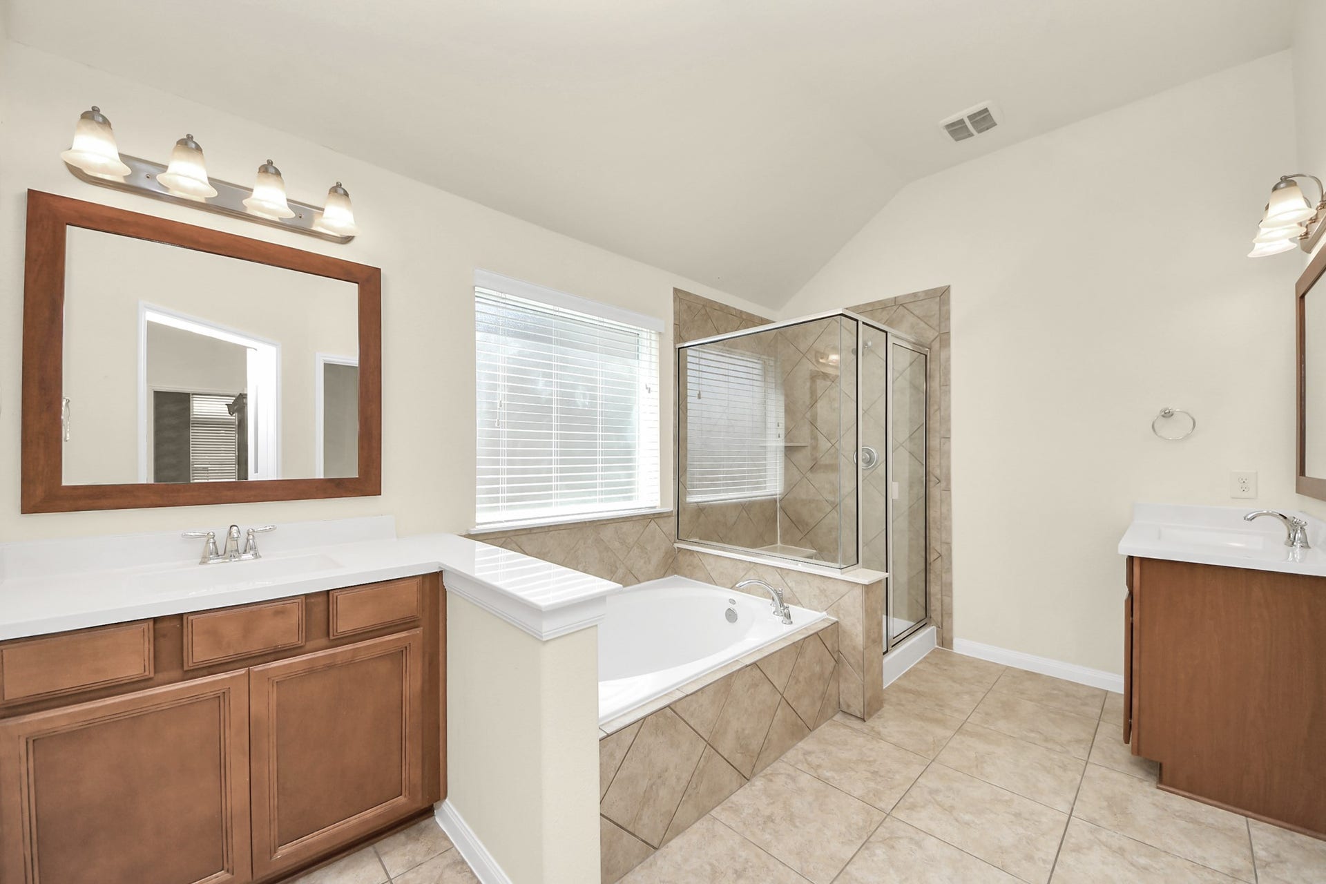 12906 Millstream Bend Lane, Tomball, TX 77377 Spacious bathroom with elegant tile flooring, featuring a large soaking tub and a separate glass-enclosed shower, complemented by dual vanities with ample cabinetry.
