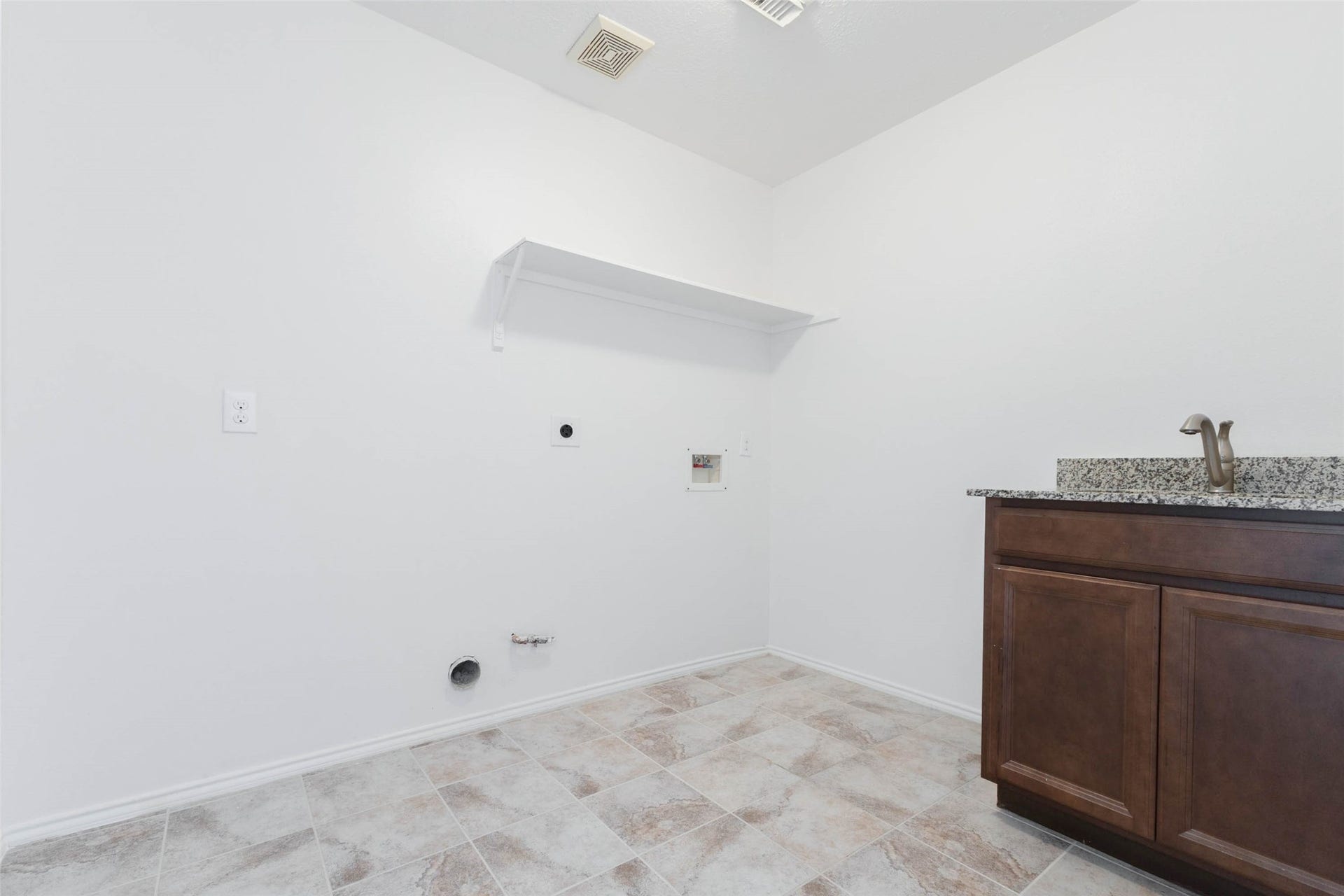 6302 Briar Canyon Court, Katy, TX 77450 This spacious laundry room offers a convenient & functional workspace featuring a granite-topped utility sink with rich wood cabinetry for additional storage. Neutral tile flooring, fresh interior paint, & overhead shelving complement the practical design. *