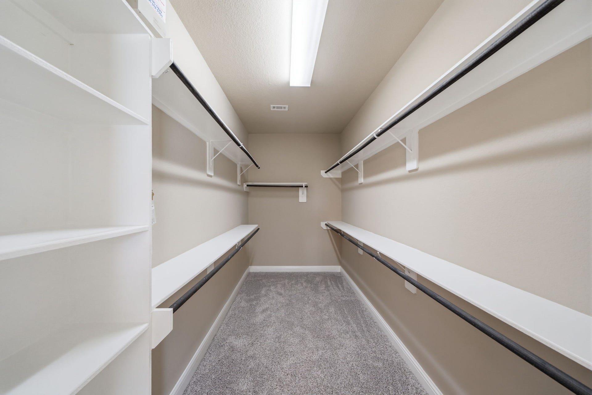 18818 Wichita Trail, Magnolia, TX 77355 Expansive walk-in closet in the primary suite features custom shelving, multiple hanging rods, and soft carpet flooring.