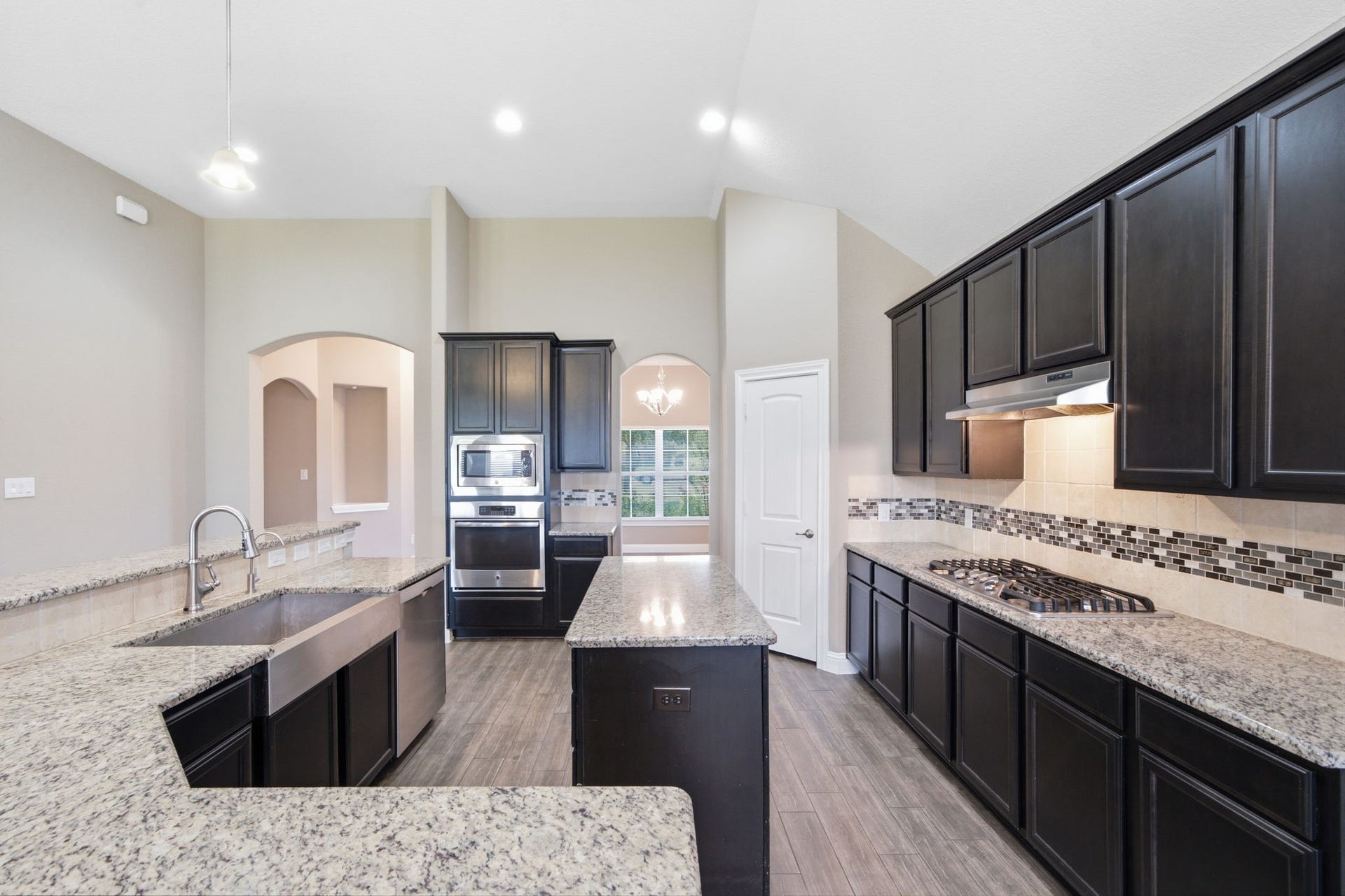 18818 Wichita Trail, Magnolia, TX 77355 Sleek granite countertops, rich dark cabinetry, and high-end stainless steel appliances including a gas cooktop define this spacious kitchen. The open layout features a central island, a convenient breakfast bar, and durable wood-look tile flooring.