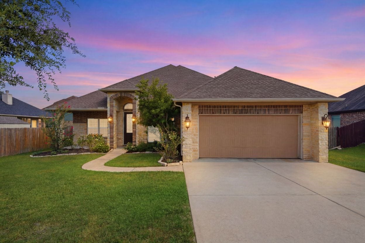 18818 Wichita Trail, Magnolia, TX 77355 Welcoming stone and brick exterior defines 18818 Wichita Trail, a single-story home featuring an attached two-car garage and a curved walkway leading to a private front patio entryway.