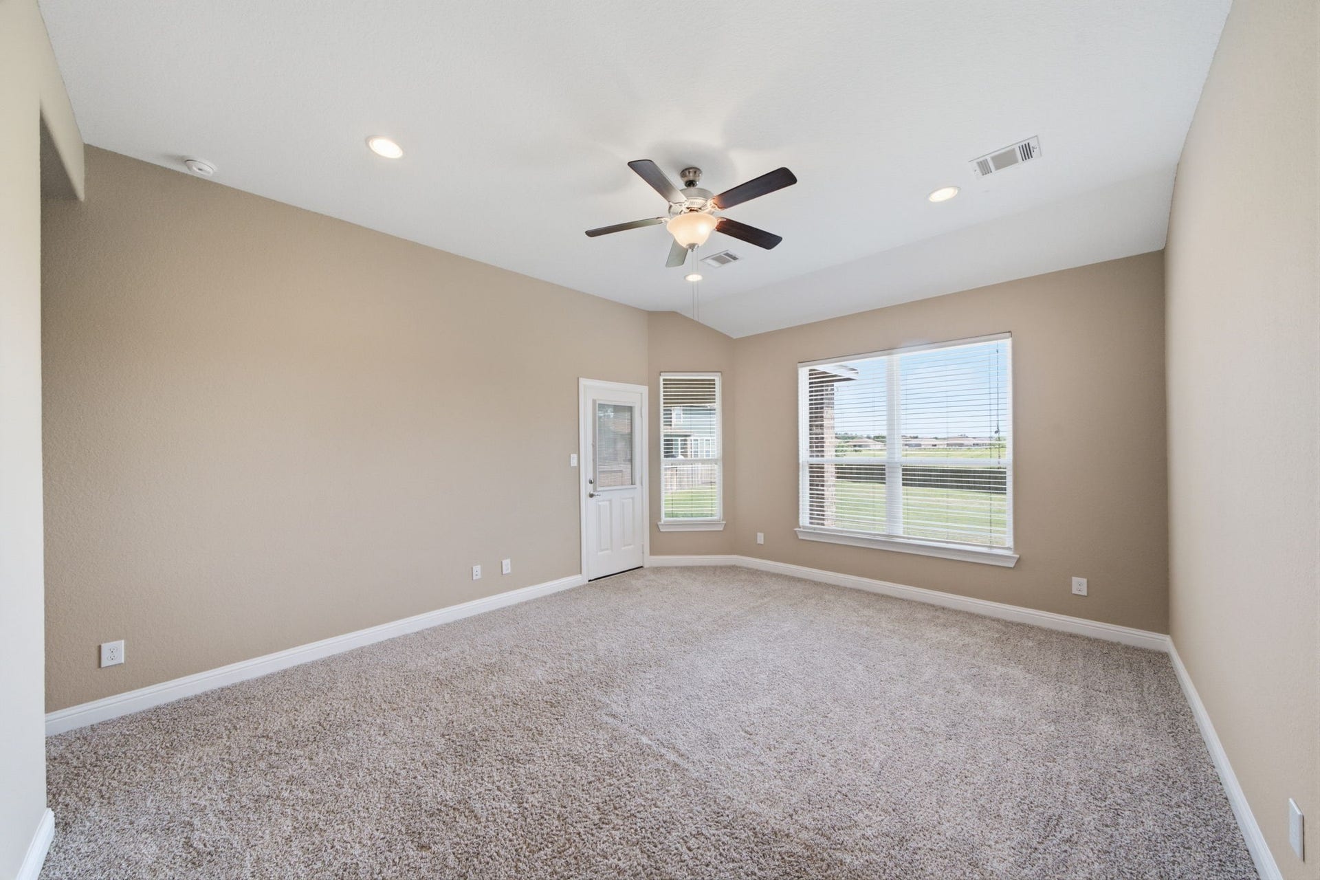 18818 Wichita Trail, Magnolia, TX 77355 Positioned on the first floor, the spacious primary bedroom features a vaulted ceiling, plush carpet flooring, and private access to the backyard. Large windows overlook the open green space behind the property, providing a serene view with no back neighbors.