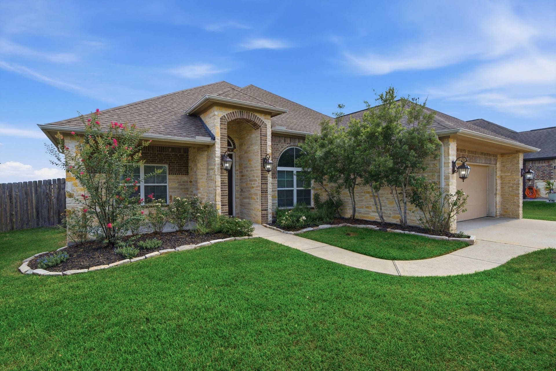 18818 Wichita Trail, Magnolia, TX 77355 Beautiful stone and brick facade showcases a striking arched entryway, a double-wide driveway, and a two-car garage. Neatly manicured landscaping, established trees, and a curved sidewalk enhance the front yard of this single-story residence.