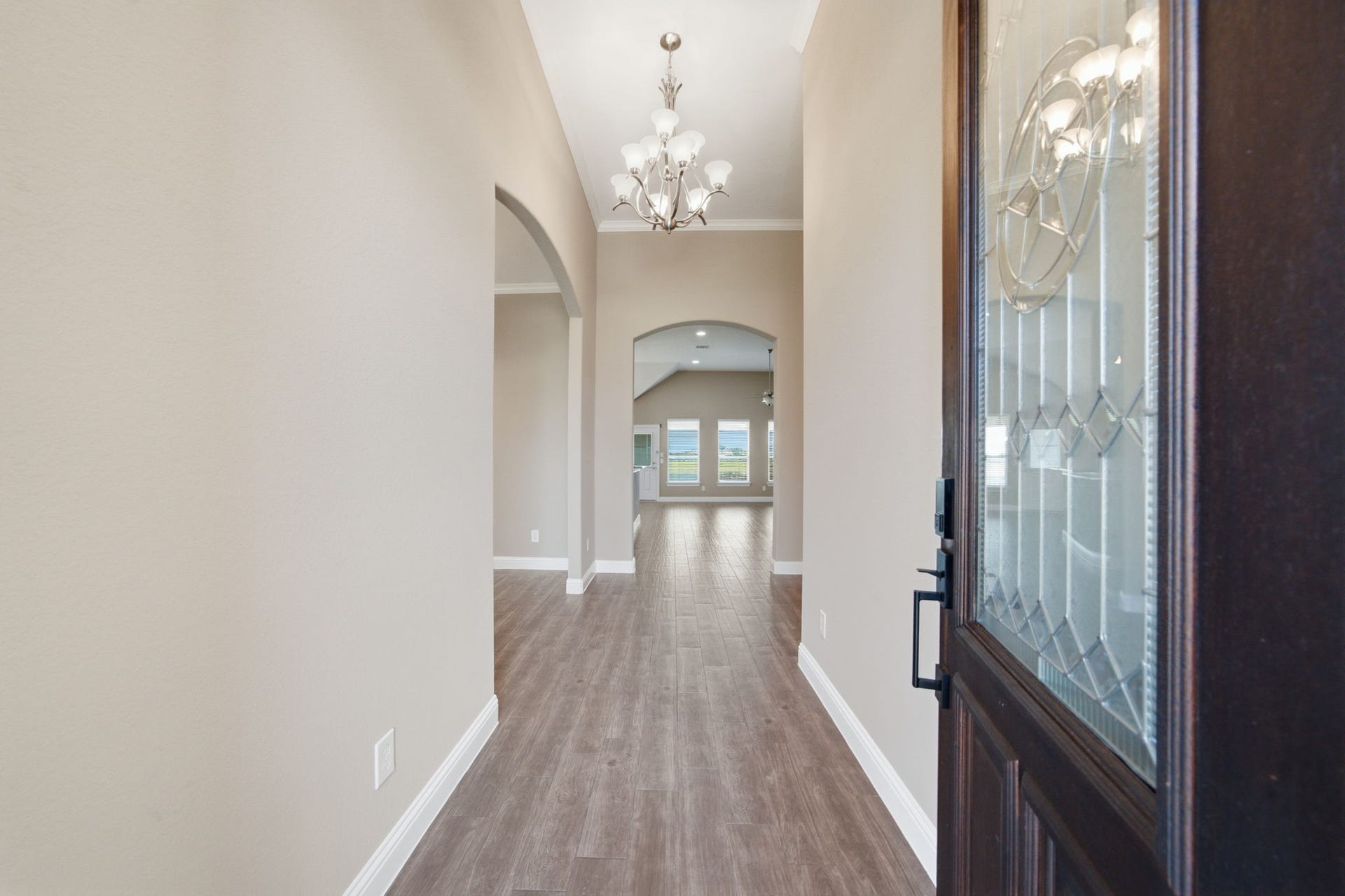 18818 Wichita Trail, Magnolia, TX 77355 Elegant front door with decorative leaded glass inserts opens to a welcoming foyer adorned with an arched doorway, tile flooring, and a classic chandelier. The elongated entryway offers clear sightlines leading straight into the open living spaces.