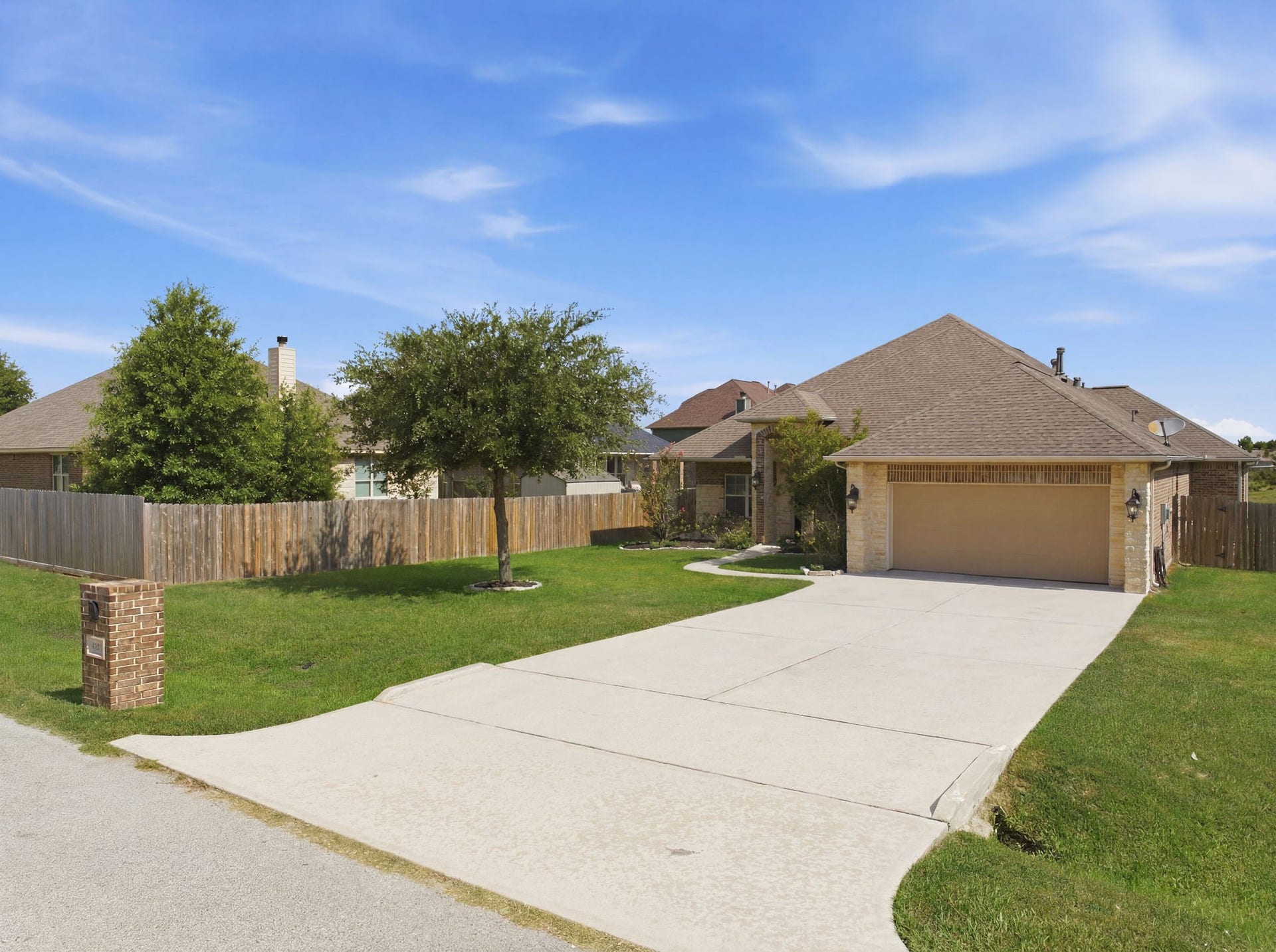 18818 Wichita Trail, Magnolia, TX 77355 Double-wide driveway leads to a two-car garage, framed by a sprawling front lawn and a brick mailbox.
