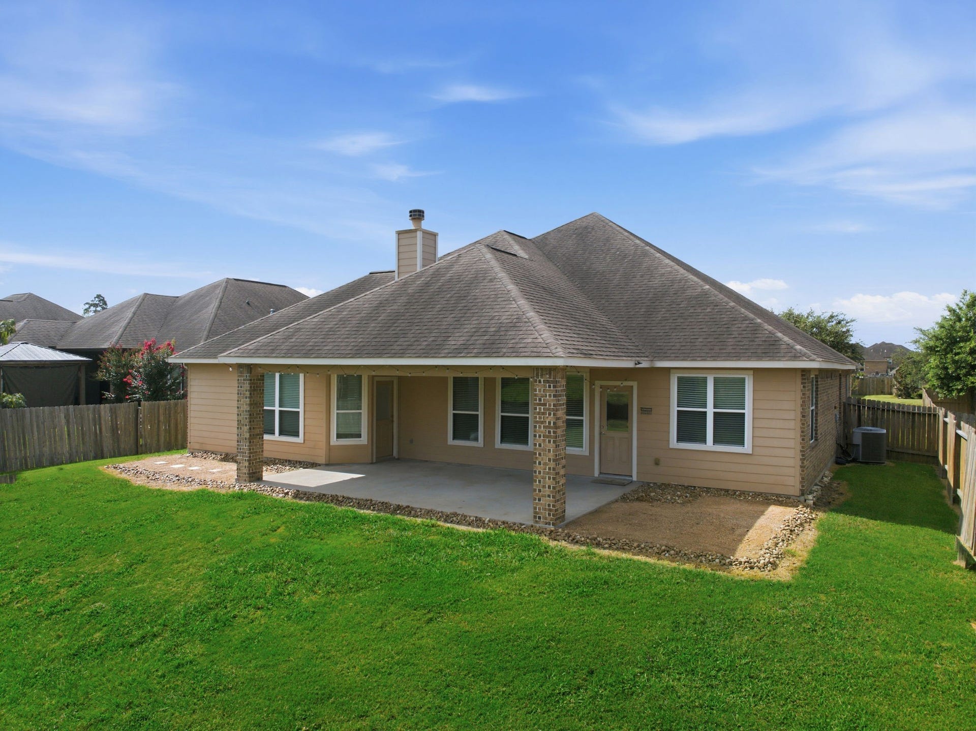 18818 Wichita Trail, Magnolia, TX 77355 Sprawling green lawn frames this back elevation, showcasing a covered patio with robust brick columns and a private fenced yard with no back neighbors.