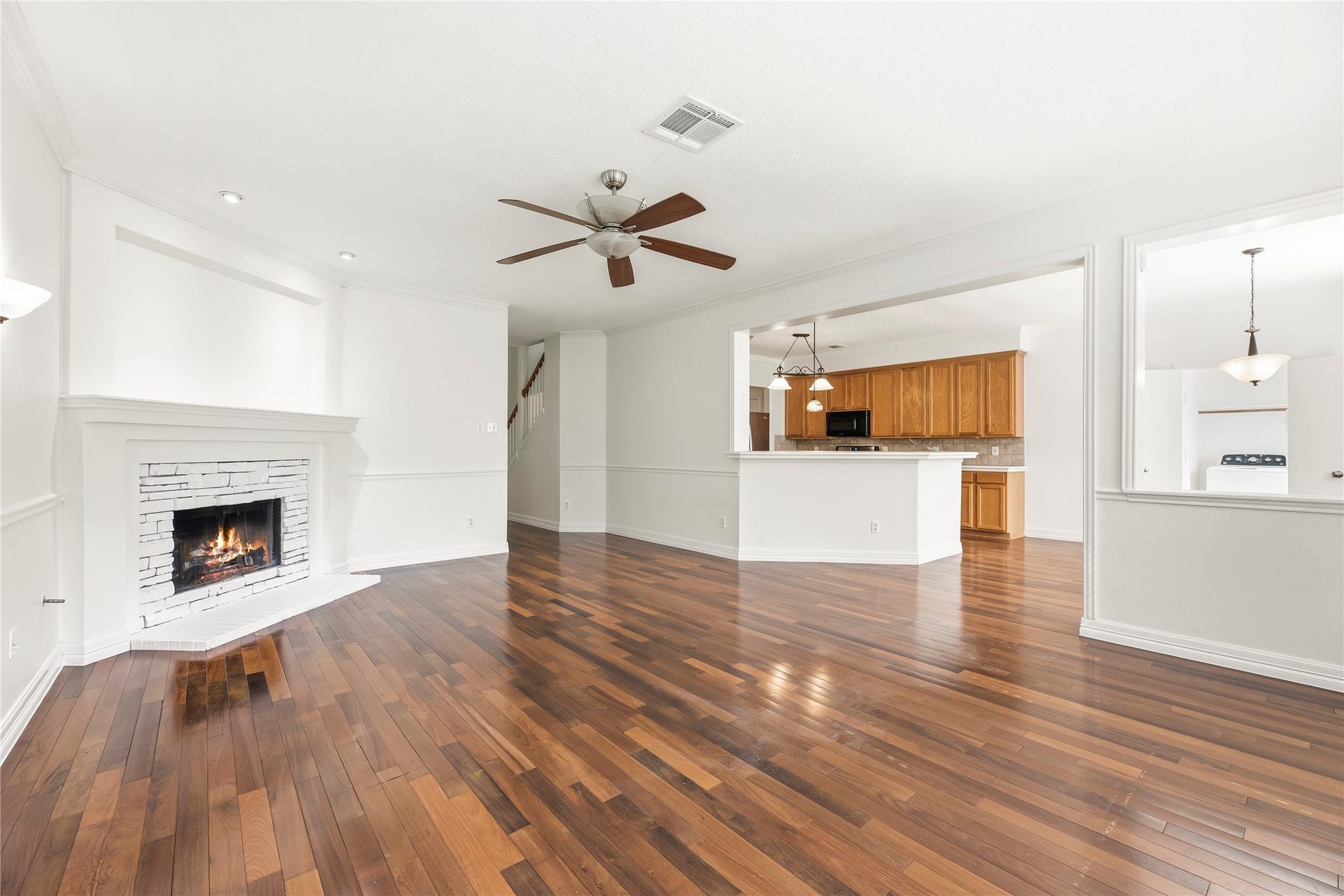 3422 Powell Way, Missouri City, TX 77459 Bright and energizing living room, featuring ceiling fan, beautiful fireplace, wood floors, and fresh paint.