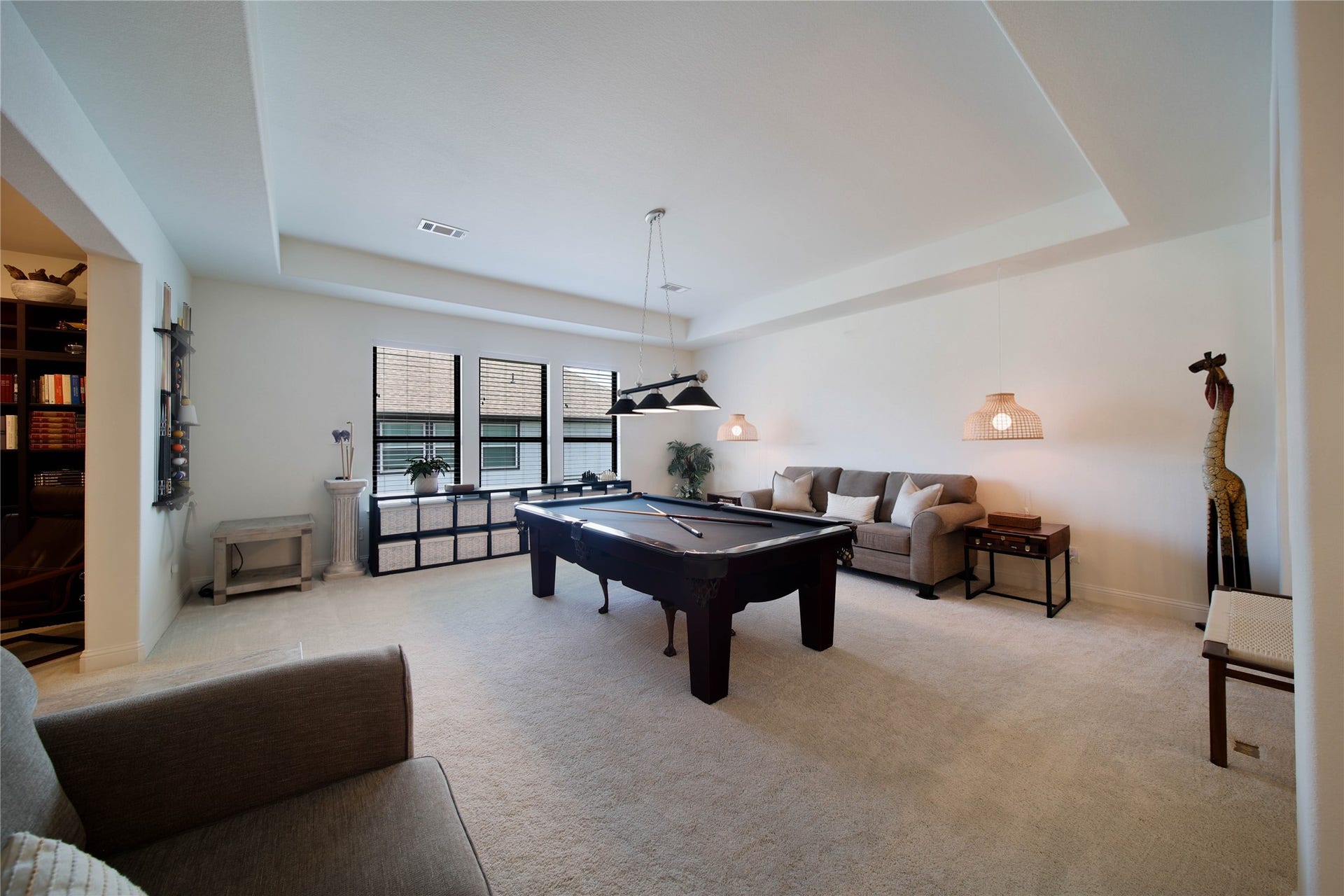 The spacious game room features a stylish tray ceiling, adding architectural interest and an elevated touch to this versatile space.