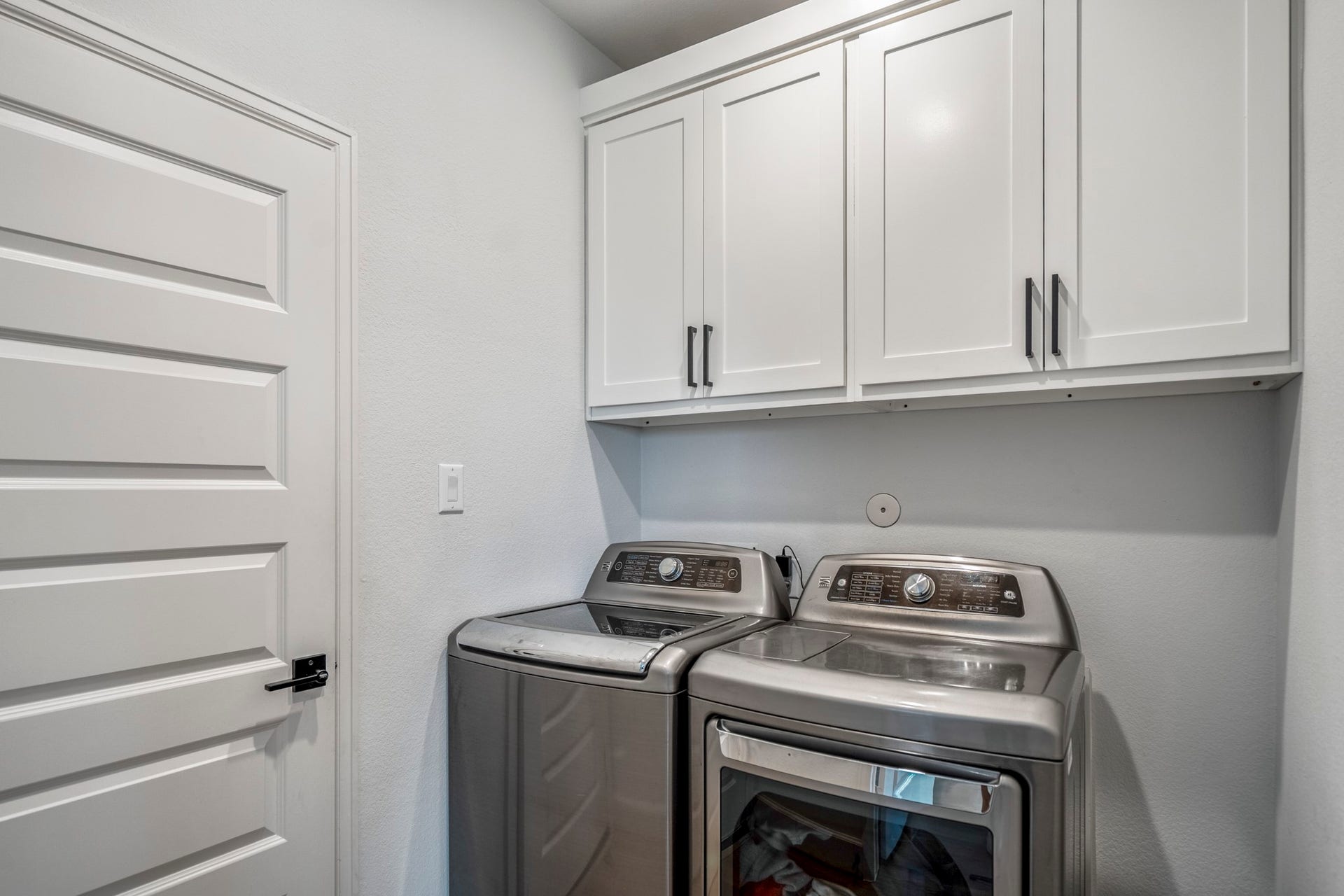 304 Mullins Court, Montgomery, TX 77316 This laundry room features sleek white cabinets for storage and a clean, minimalistic design.