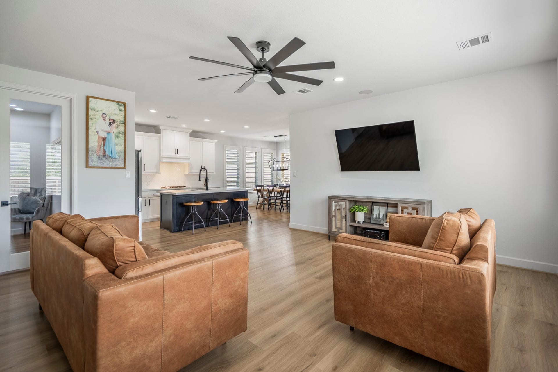 304 Mullins Court, Montgomery, TX 77316 This modern living space features an open floor plan with a spacious kitchen, sleek island, and dining area. The room is bright with natural light and has stylish finishes at every turn.