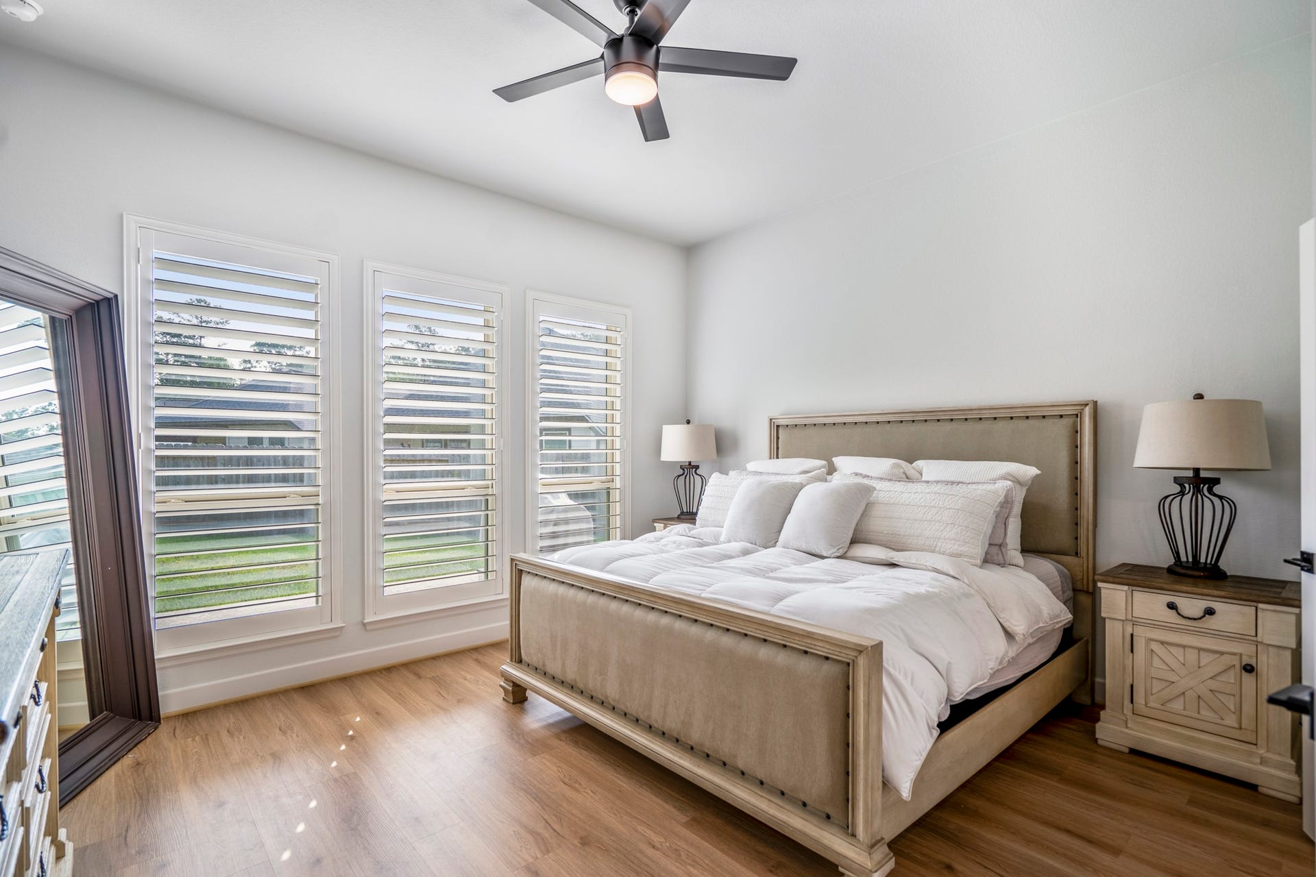 304 Mullins Court, Montgomery, TX 77316 This first-floor primary suite features large windows with plantation shutters, allowing natural light to fill the space. Take note of those beautiful, upgraded floors that continue throughout.