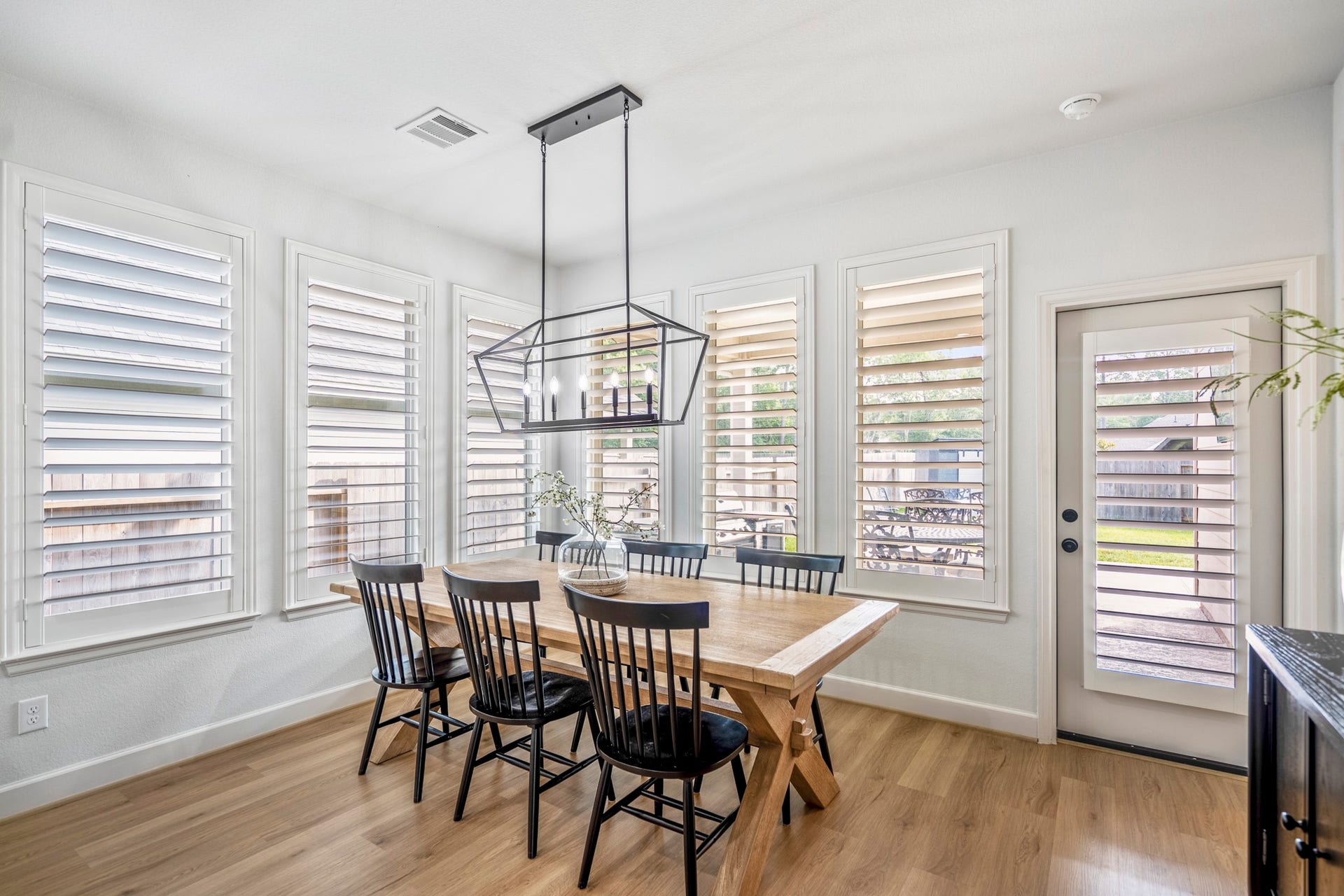 304 Mullins Court, Montgomery, TX 77316 Overlooking the extended patio and generously sized lot, this breakfast space adorned with the contemporary light fixture is surrounded by a wall of windows, offering a peaceful feel.