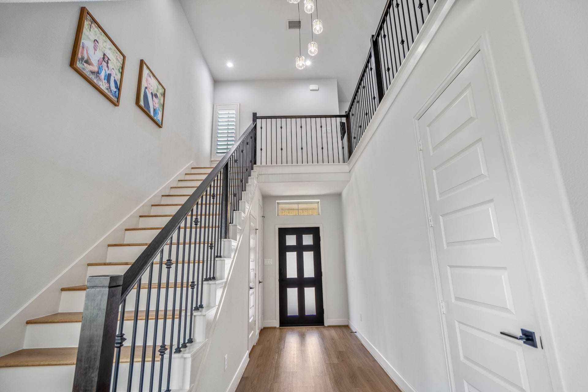 304 Mullins Court, Montgomery, TX 77316 This entryway showcases a bright, modern look with a high ceiling, elegant staircase with an upgraded black railing. The space is accented by LVP flooring and contemporary light fixtures, creating a welcoming and stylish first impression.
