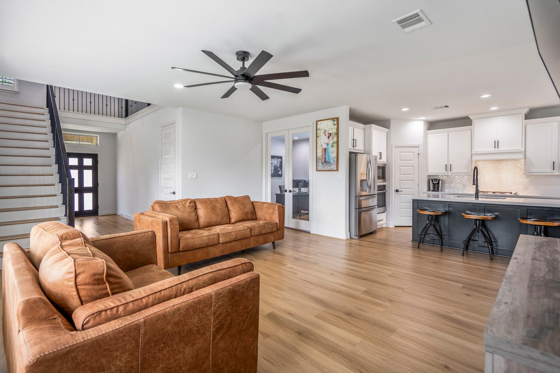 304 Mullins Court, Montgomery, TX 77316 This modern open-concept living area features sleek LVP floors, a stylish kitchen with white cabinets and stainless-steel appliances, and a cozy seating area. The space is bright, with a contemporary feel.