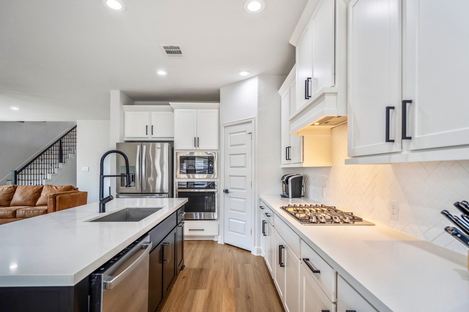 304 Mullins Court, Montgomery, TX 77316 It features a gas stove, built-in oven, and ample counter space, all illuminated by recessed lighting. The open layout flows into the living area with a glimpse of a staircase.