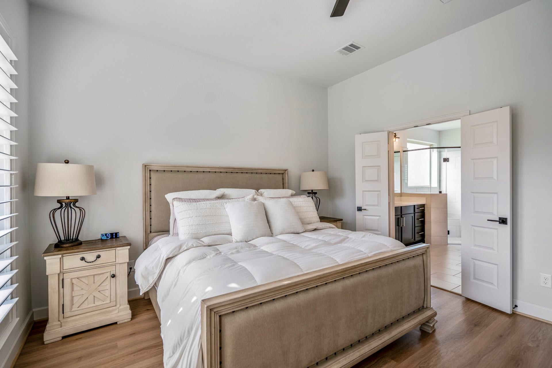 304 Mullins Court, Montgomery, TX 77316 The primary bedroom boasts large windows allowing natural light to fill the space, and an en-suite bathroom beyond the double doors.