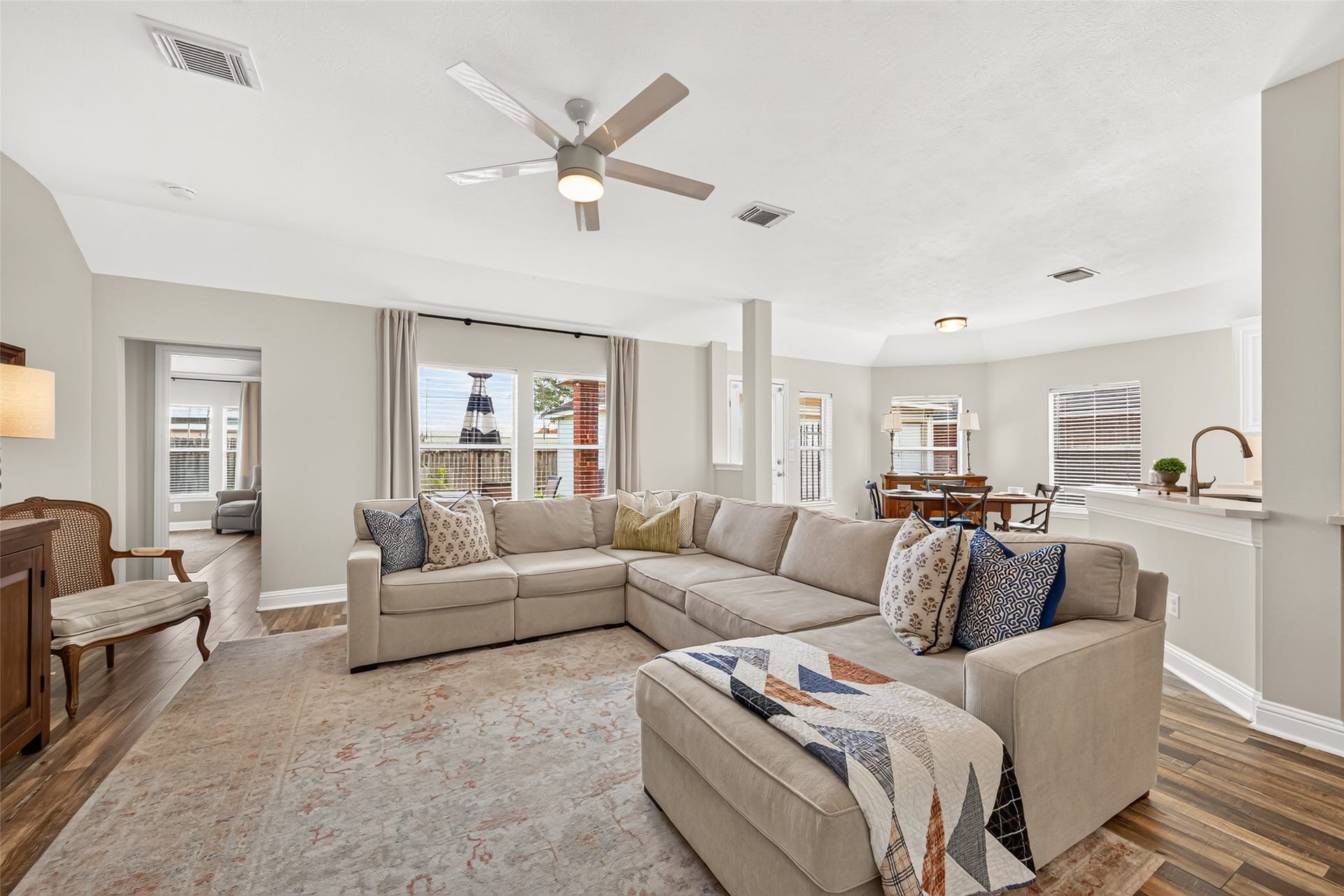 High ceilings, continuous multi-tone wood-look plank floors, and a sleek ceiling fan enhance the open, airy feel of the layout.