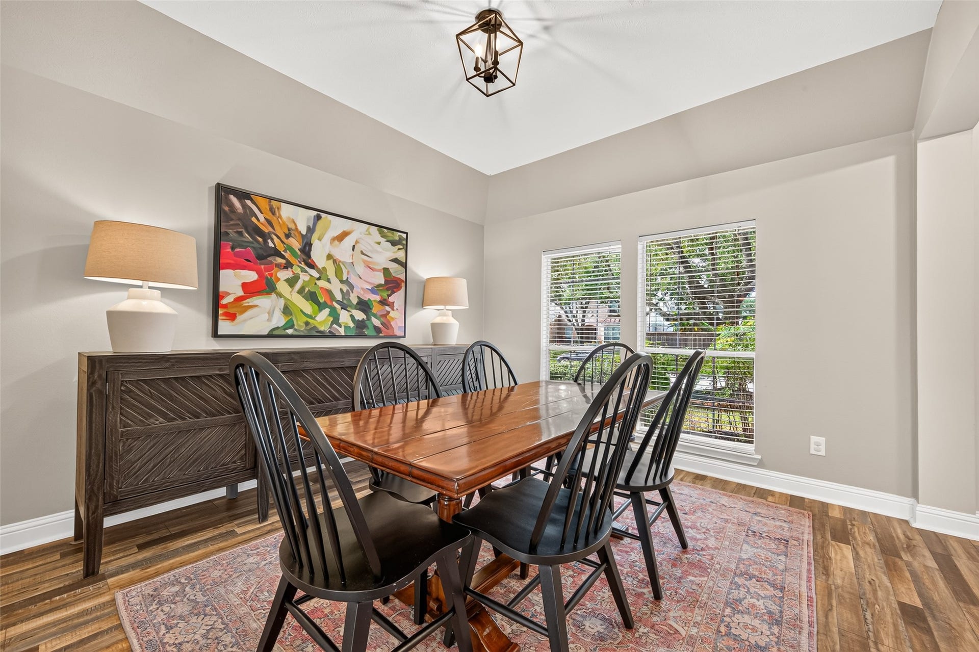 Highlighted by a statement geometric lantern chandelier, the room features subtle vaulted ceiling angles, smooth neutral walls, and crisp white baseboards that emphasize the space's elegant architectural structure.