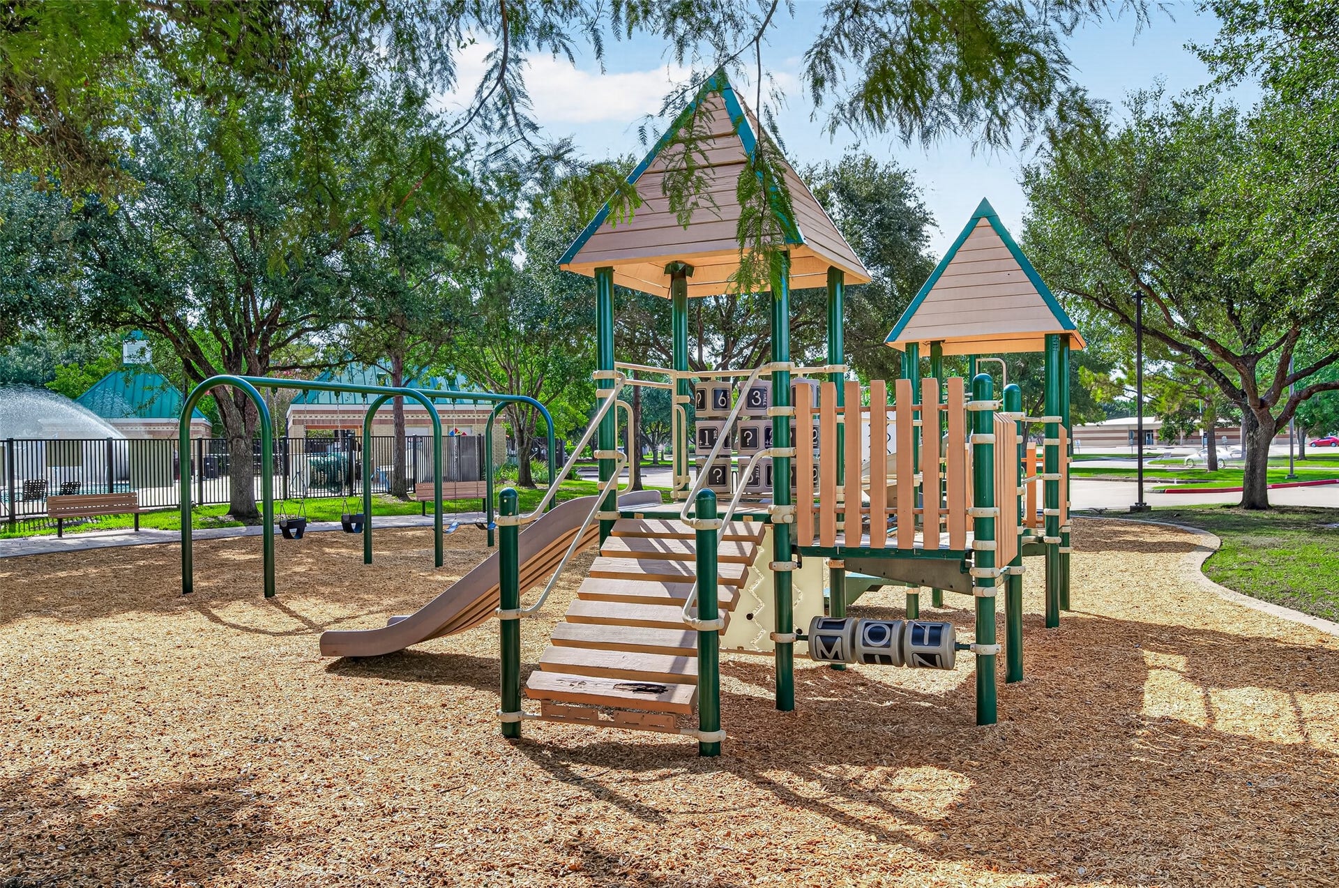 Families will love this vibrant, well-maintained neighborhood playground and park area. Built on a soft, protective wood-chip surface bordered by concrete curbing, the playground features multi-level play structures, spiral slides, climbing ladders, and covered towers. Surrounded by towering shade trees, smooth concrete walking paths, and green open space, this outdoor setting offers an inviting space for kids to play and explore.