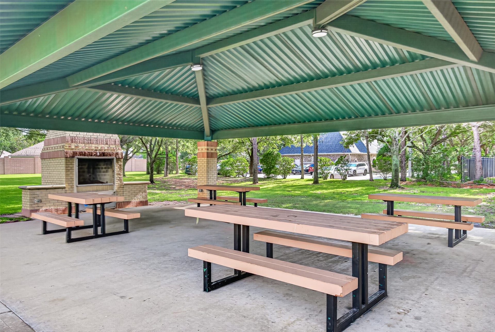 Perfect for weekend gatherings and community celebrations, this spacious covered park pavilion provides the ideal setup for outdoor dining and entertaining. Sheltered beneath a sturdy metal roof with overhead lighting, the pavilion features multiple heavy-duty picnic tables set on a clean concrete pad.