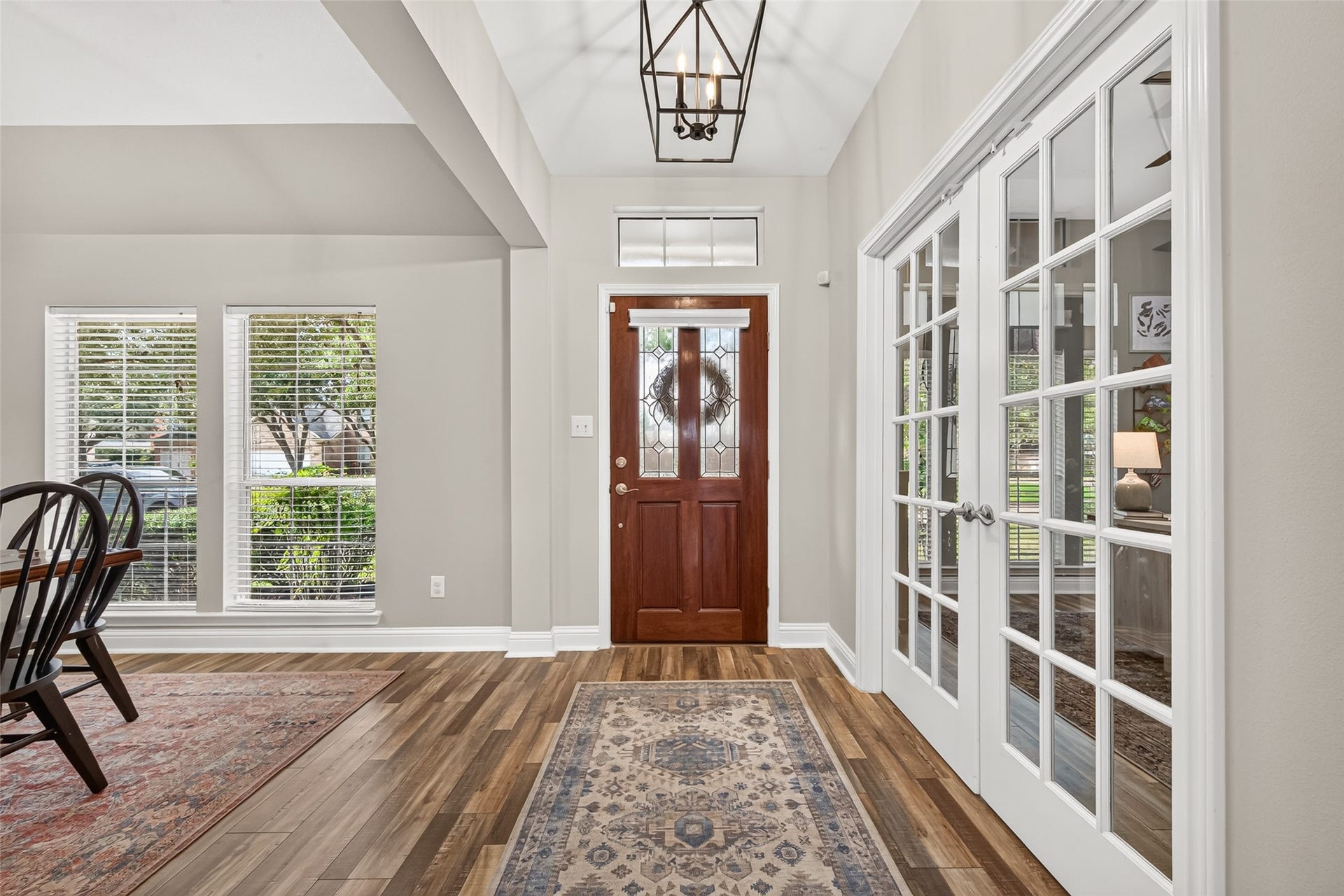 Directly off the entryway, double French glass doors swing open to reveal a flexible home office, study, or formal room accented by warm brass hardware. To your right, the formal dining space showcases rich architectural framing, perfect for hosting intimate dinners or festive gatherings.