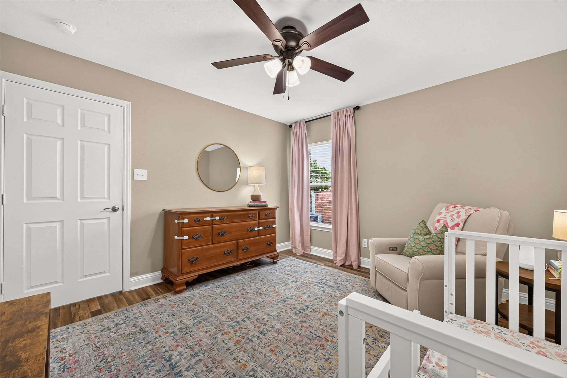 Another beautifully proportioned bedroom, this warm and inviting space features soft beige walls paired with rich, multi-tone wood-look plank flooring and crisp white baseboards.