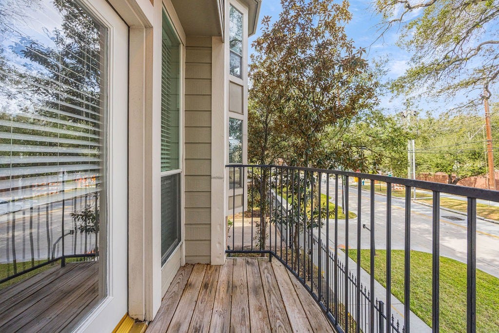 An upper level balcony framed by mature trees and city views.