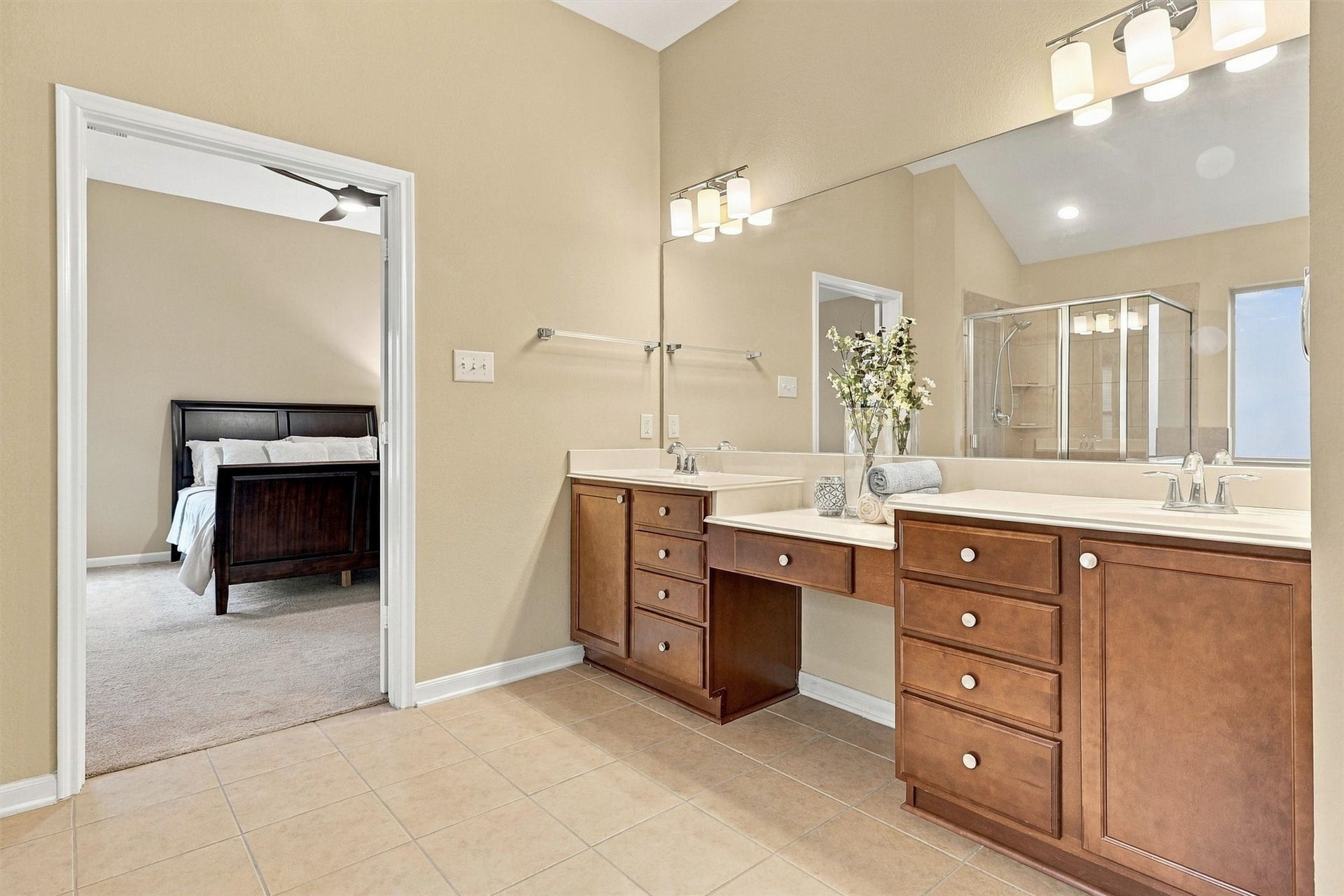 24015 Orange Orchard Lane, Katy, TX 77493 Separate sinks and a long mirror across the vanity wall, with the bedroom visible through the doorway behind.