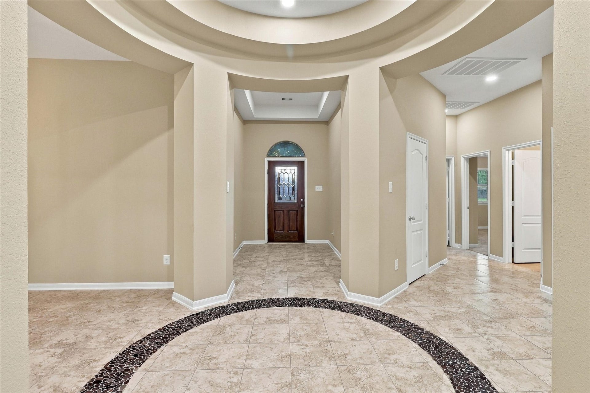 24015 Orange Orchard Lane, Katy, TX 77493 The rotunda foyer runs straight to the front door under a domed ceiling, with an inlaid river-rock ring set into the tile at its center.