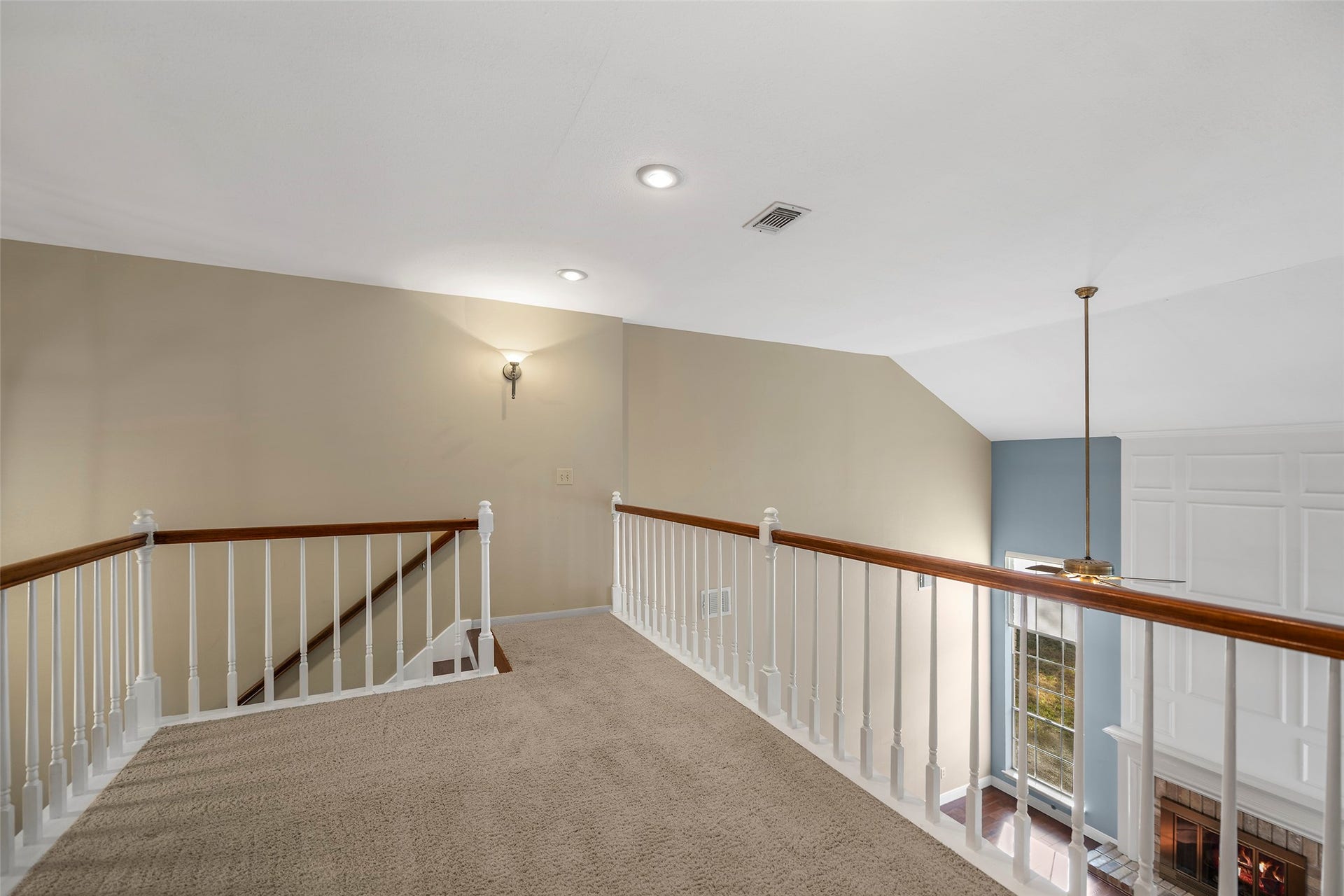 2631 Woodsboro Drive, Spring, TX 77388 Charming upstairs landing with plush carpeting and elegant wood railing, offering a cozy overlook into the bright, inviting space below.