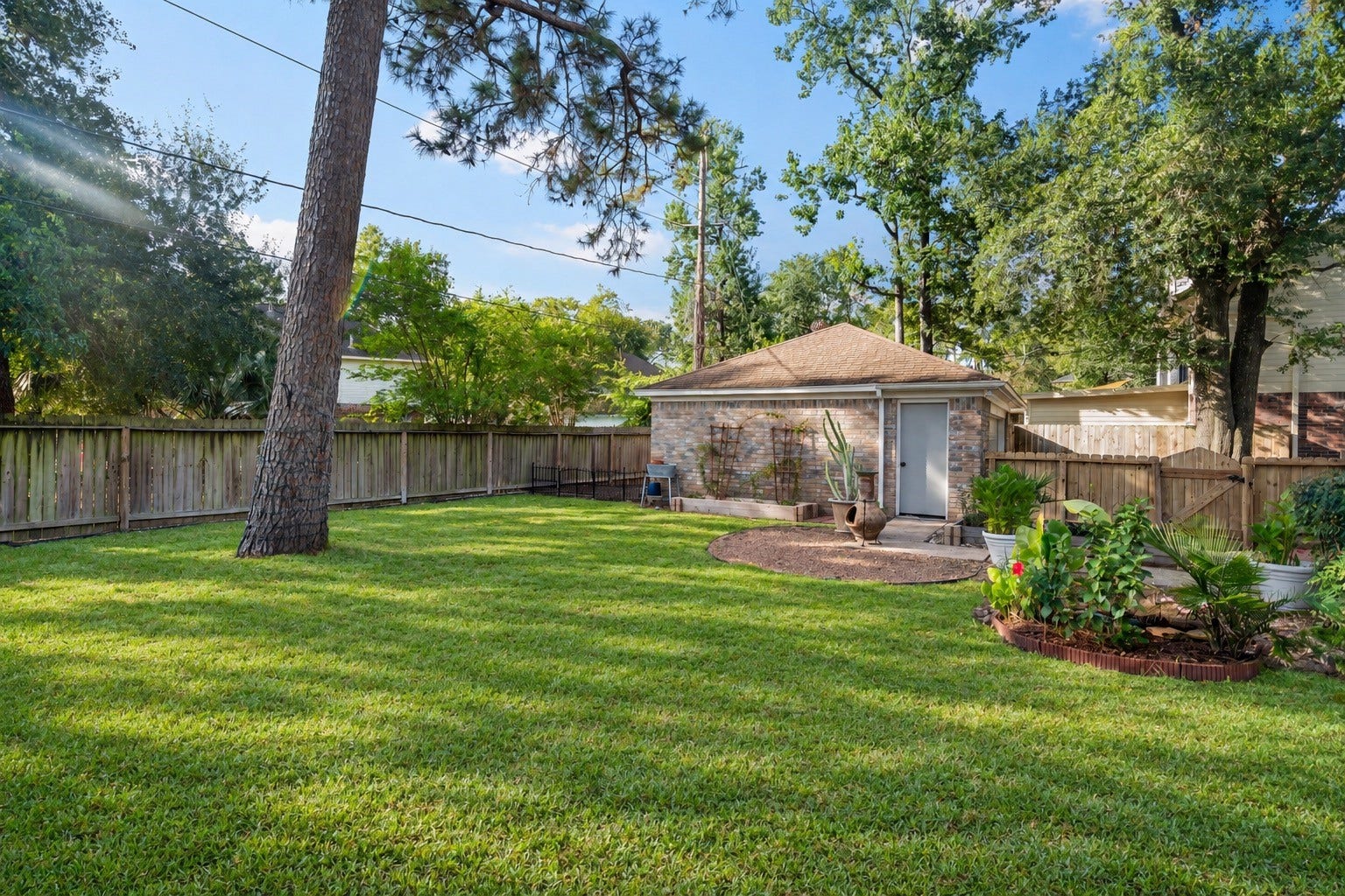 2631 Woodsboro Drive, Spring, TX 77388 Expansive backyard with lush green lawn, mature trees, and a charming brick garden shed, perfect for outdoor relaxation and gardening.