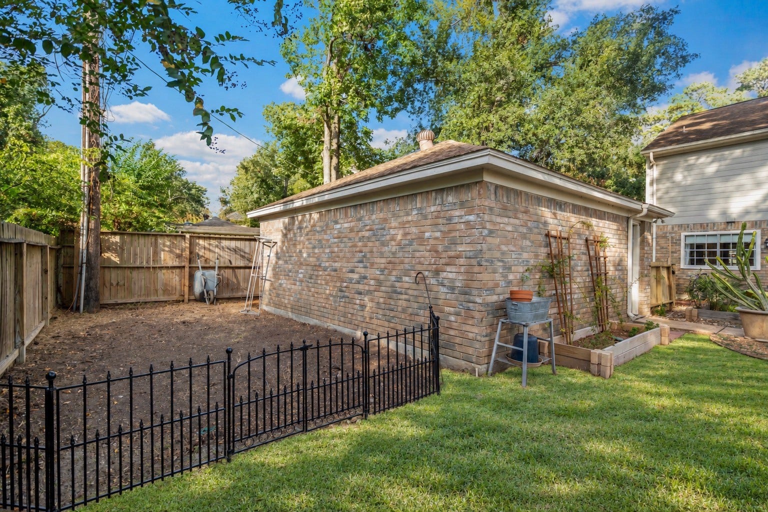 2631 Woodsboro Drive, Spring, TX 77388 Charming backyard with a brick structure, lush greenery, and a cozy fenced garden area perfect for outdoor activities and gardening.