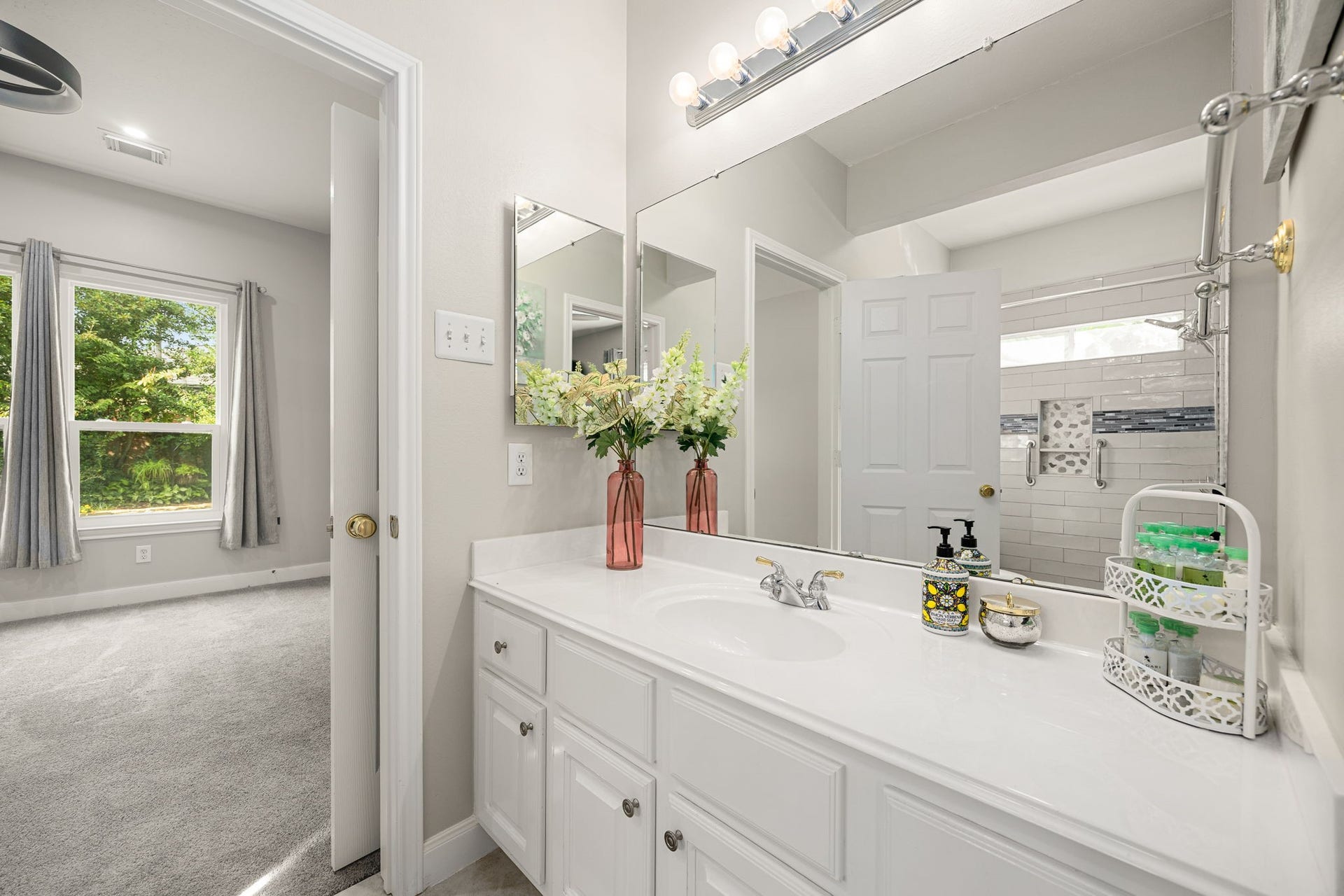 4110 Garden Cove Court, Katy, TX 77494 This space features a long white vanity with exceptional counter space, a large mirrored grooming area, and bright vanity lighting. Conveniently situated adjacent to a spacious secondary bedroom, this layout offers excellent functionality for children or overnight guests.