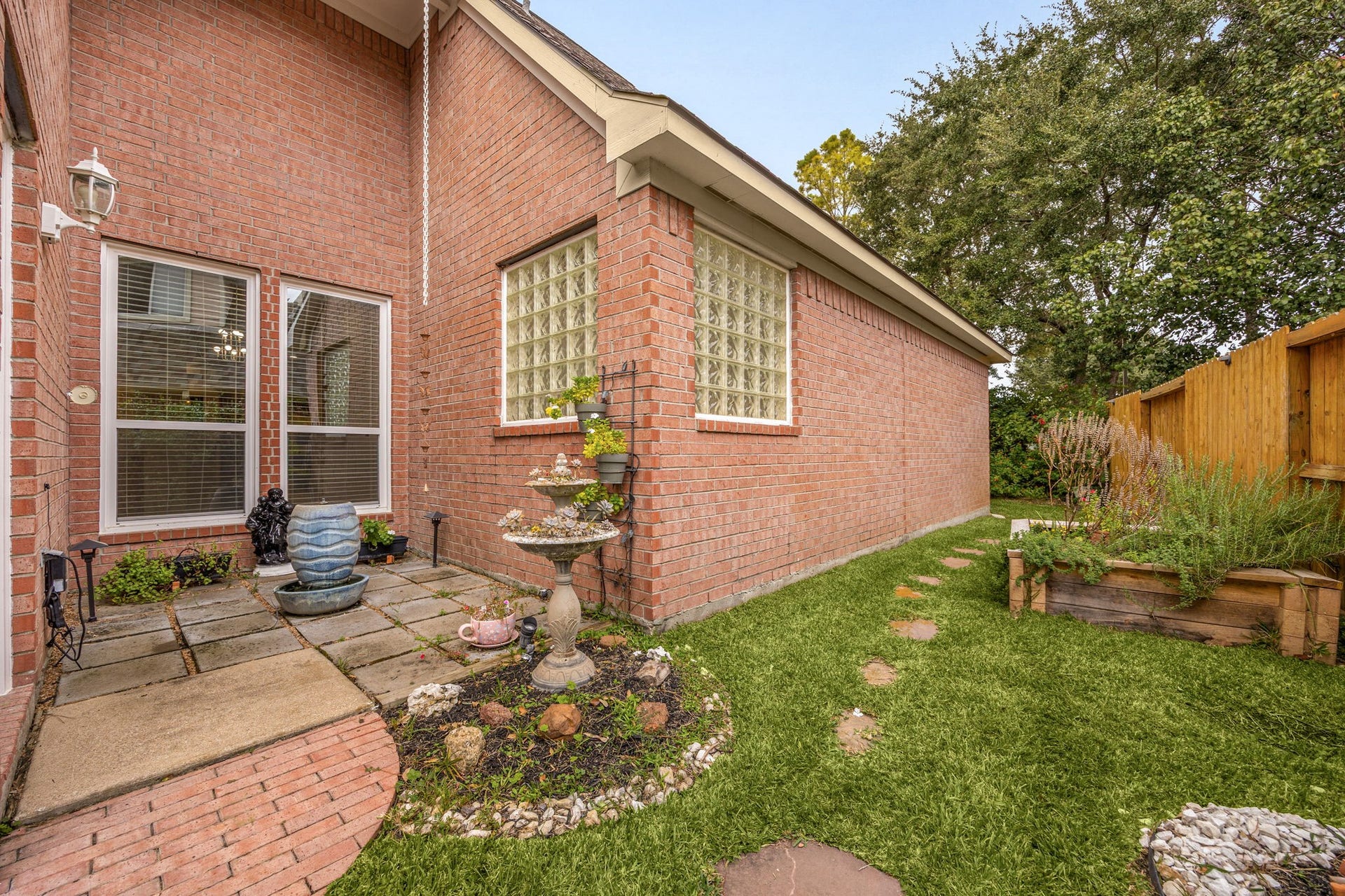 4110 Garden Cove Court, Katy, TX 77494 This beautifully landscaped corner showcases a stepping-stone path leading to a built-in stone planter bed, perfect for a home garden. Surrounded by classic four-sided brick architecture and private glass-block windows, it offers another peaceful outdoor pocket to enjoy your serene surroundings.