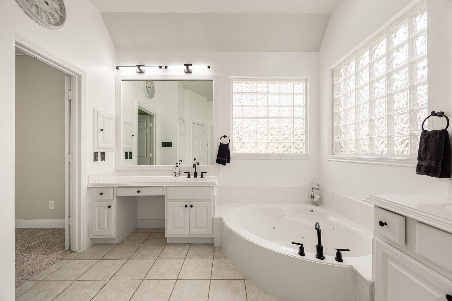 4110 Garden Cove Court, Katy, TX 77494 A dedicated vanity area with a knee-space makeup counter sits adjacent to the luxurious soaking tub, while premium glass-block windows flood the room with natural light without compromising privacy. The doorway opens directly into the massive primary closet.