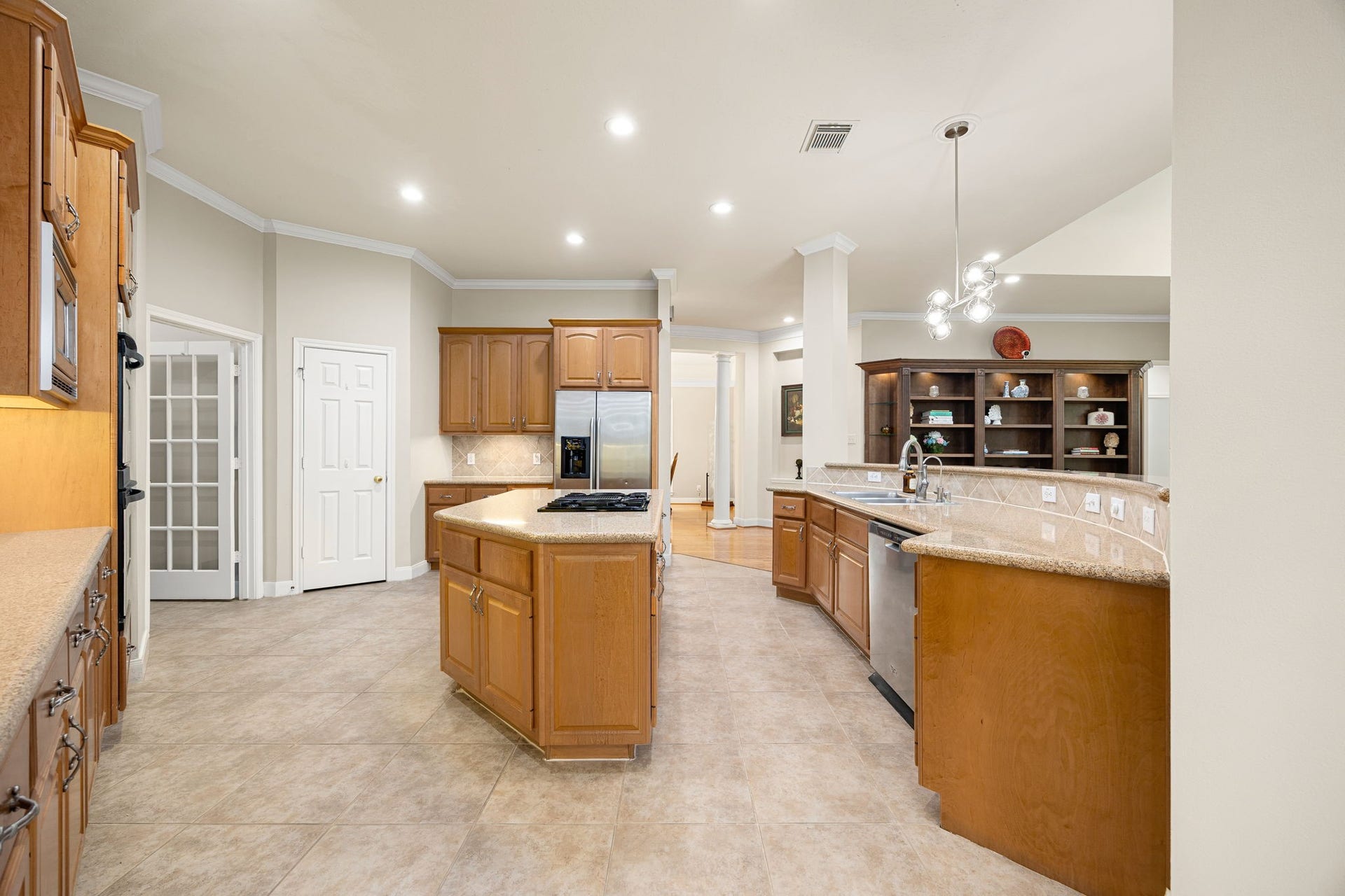 4110 Garden Cove Court, Katy, TX 77494 This reverse angle highlights the massive walk-in pantry hidden behind elegant French doors, a built-in workspace desk, and an expansive breakfast bar with a built-in sink and dishwasher. Every detail is optimized for convenience, organization, and effortless entertaining!