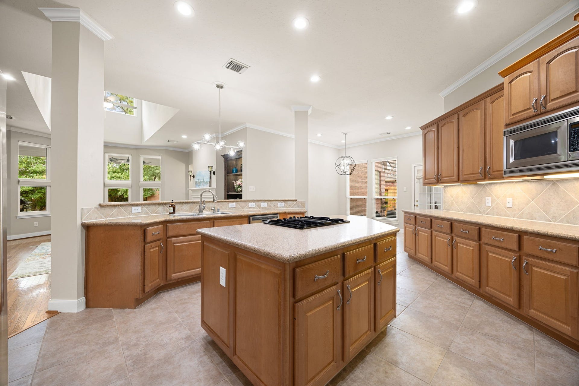 4110 Garden Cove Court, Katy, TX 77494 This perspective captures the endless counter space, sophisticated under-cabinet lighting, and an expansive breakfast bar flanking the kitchen. With views into the adjacent sunlit breakfast nook and main living areas, this layout blends functional work zones with a highly social, open-concept lifestyle.