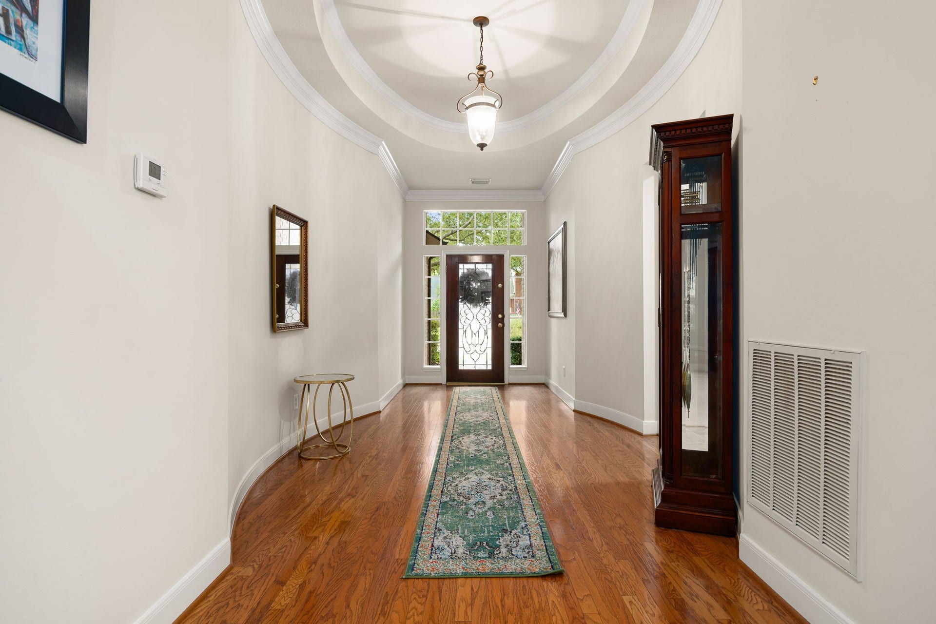 4110 Garden Cove Court, Katy, TX 77494 Step through the front door into a spectacular foyer featuring an elegant, curved architectural gallery layout. Rich, gleaming wood floors, soaring ceilings with custom tray detailing, and a classic statement light fixture seamlessly guide you toward the heart of the home.