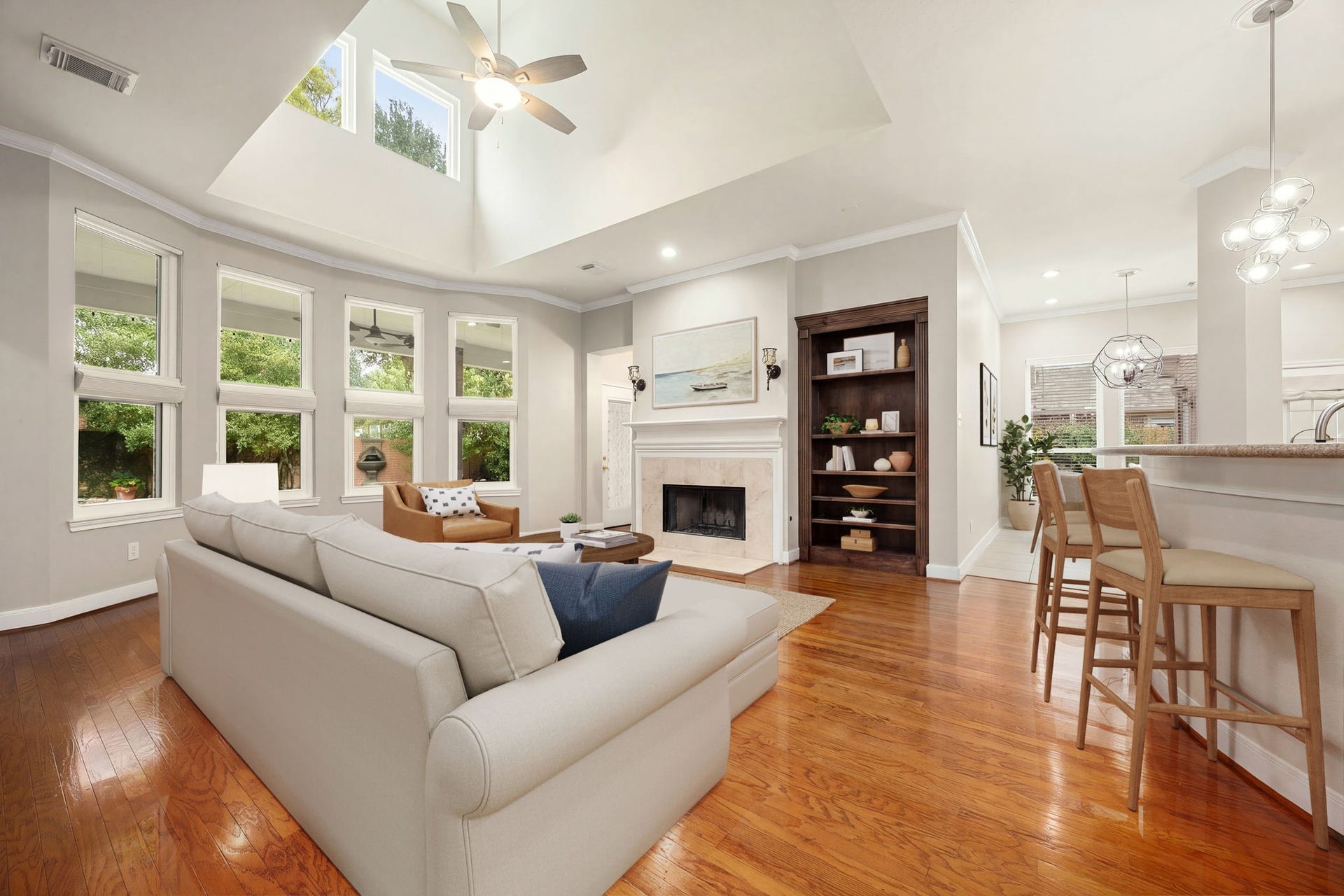 4110 Garden Cove Court, Katy, TX 77494 Sun-drenched and spacious, the family room is the heart of this open-concept layout. High, vaulted architectural ceilings and a towering wall of windows fill the space with beautiful natural light. Gleaming hardwood floors lead to a cozy fireplace flanked by beautiful custom dark-wood built-ins, with a seamless view into the adjacent kitchen and bar area.