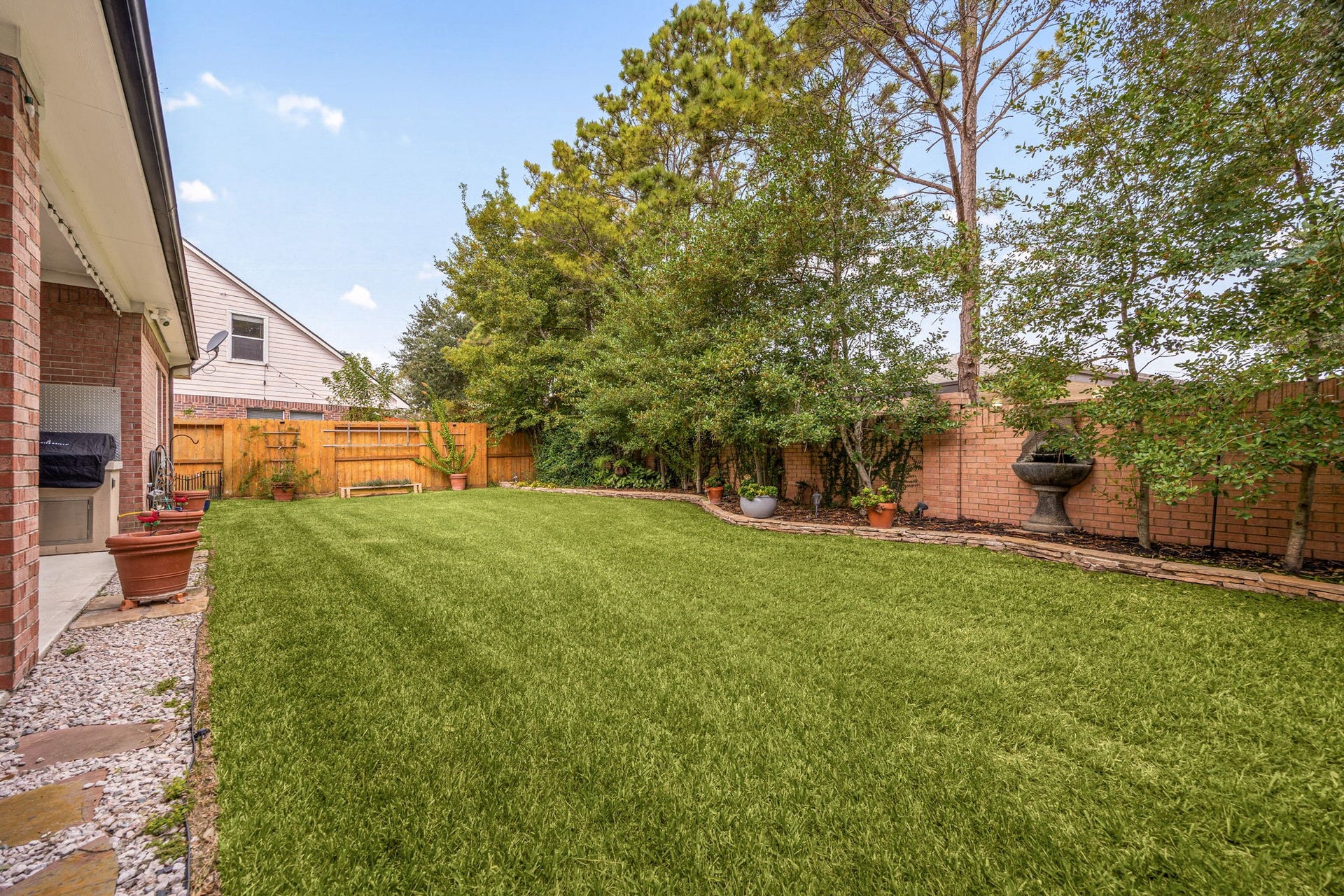 4110 Garden Cove Court, Katy, TX 77494 This wide daytime view highlights the immense scale of the lush green lawn, framed by a thick line of mature, towering privacy trees along the back fence line. Offering a pristine, sprawling space with no immediate rear windows looking down onto you, its the ultimate canvas for a future custom pool, playground, or serene outdoor retreat.