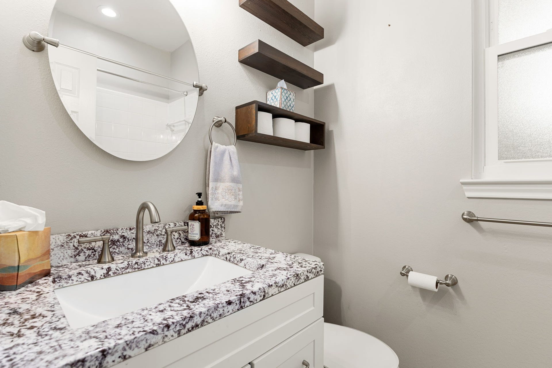 4110 Garden Cove Court, Katy, TX 77494 This bath features a premium granite vanity top with striking character, a sleek white cabinet base, and a contemporary frameless circular mirror. This beautifully updated space offers a chic and welcoming environment for family and guests alike.