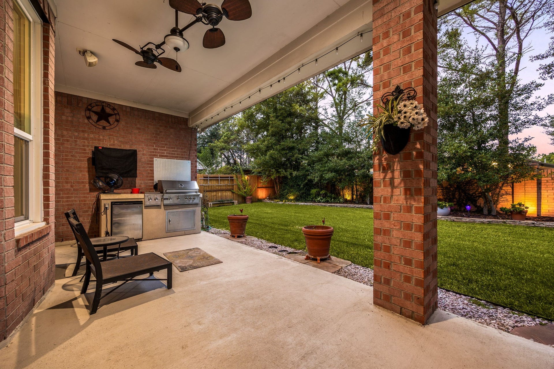 4110 Garden Cove Court, Katy, TX 77494 This reverse view of the covered patio highlights the beautifully manicured, tree-lined backyard that provides exceptional privacy. The expansive green lawn offers plenty of space for pets to run, kids to play, or even a future swimming pool, perfectly completing this remarkable Cinco Ranch home.